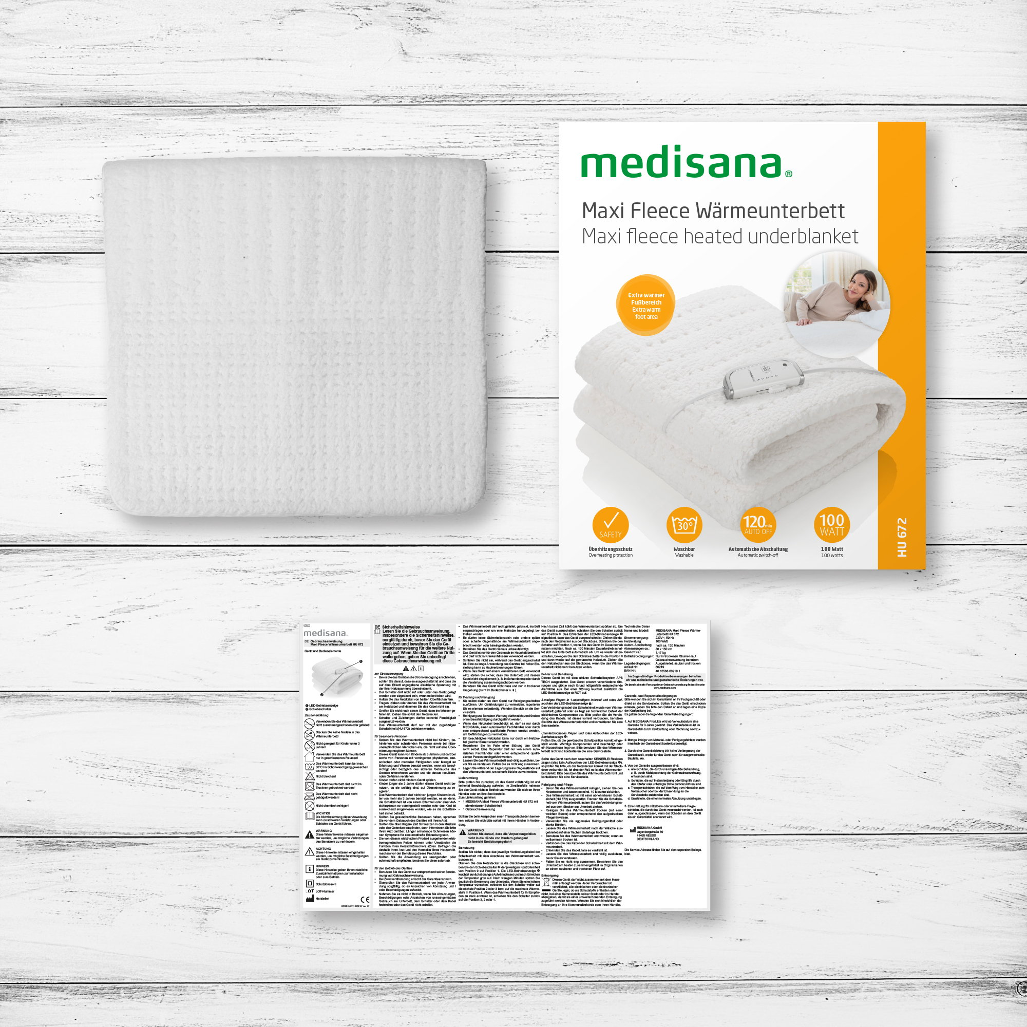 Biały elektryczny koc grzewczy z pudełkiem i jego szczegółami, na drewnianym stole.