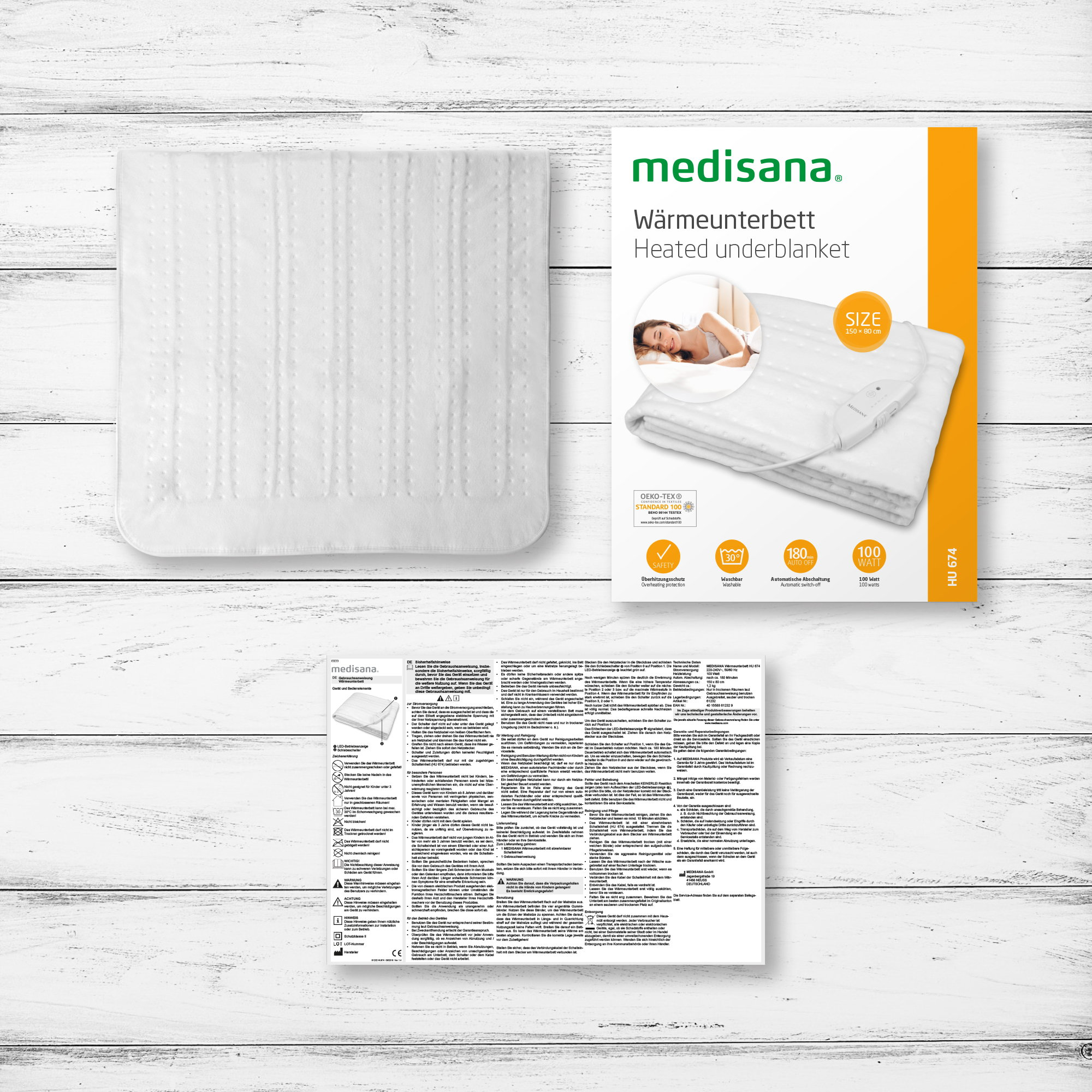 Biały podgrzewany koc, jego opakowanie i instrukcje na drewnianej powierzchni.