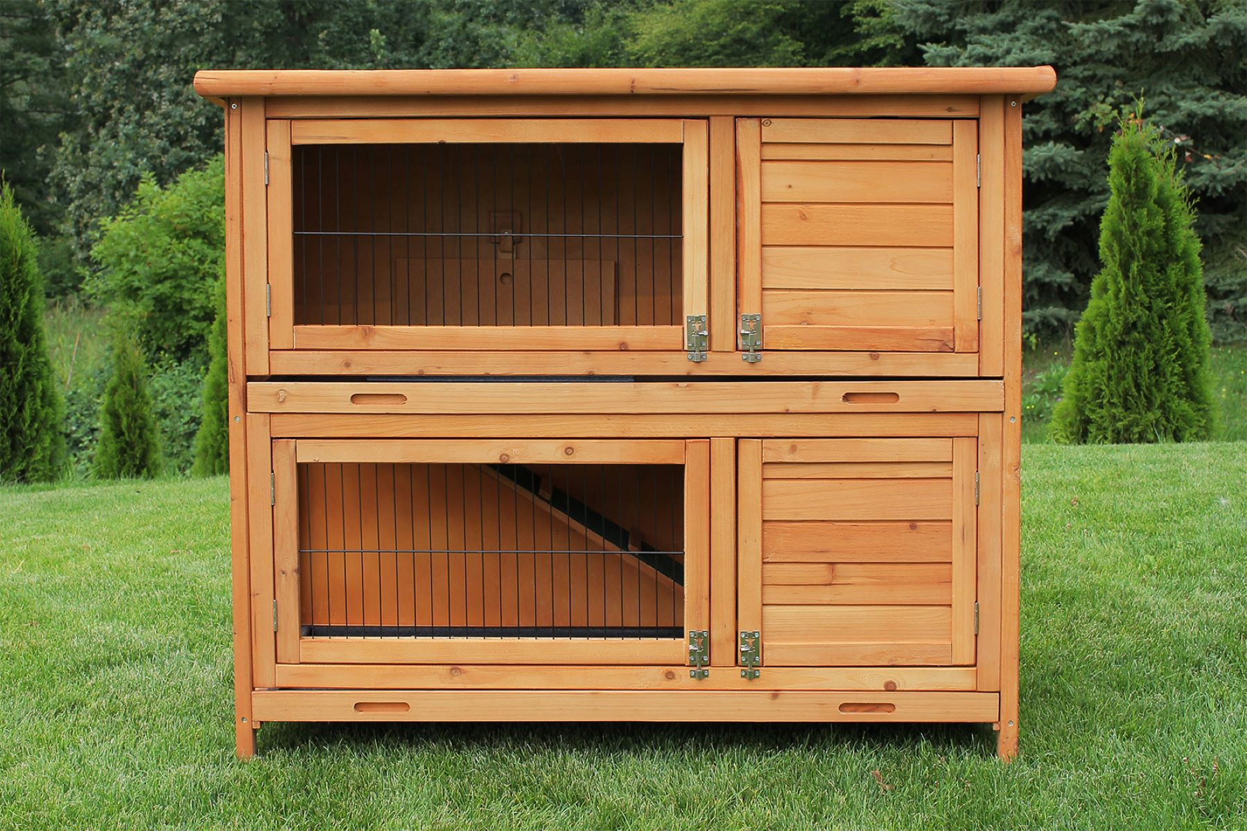 Kaninchenstall aus Holz mit zwei Etagen, auf grünem Gras.