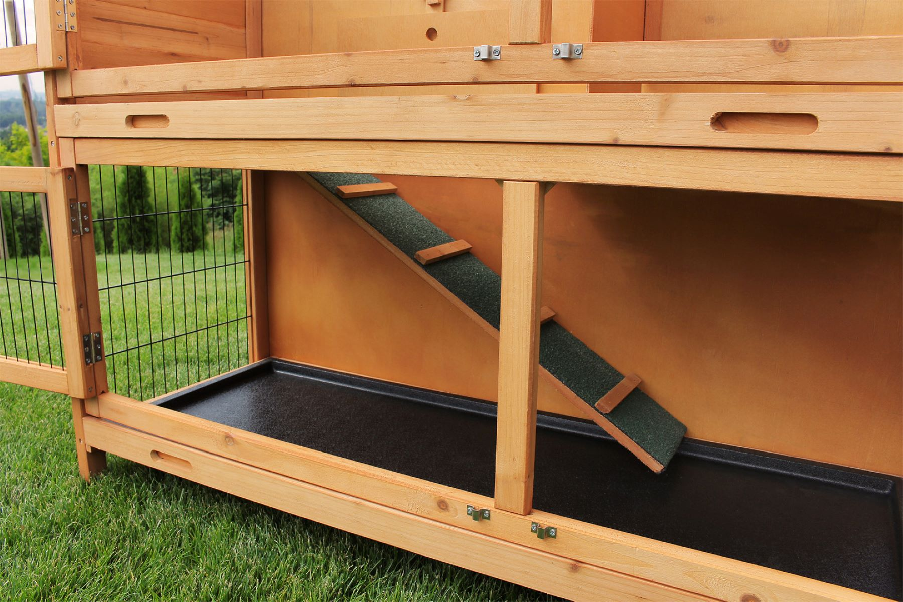 Kaninchenstall aus Holz mit Rampe, schwarzer Schale und geöffneter Drahttür.
