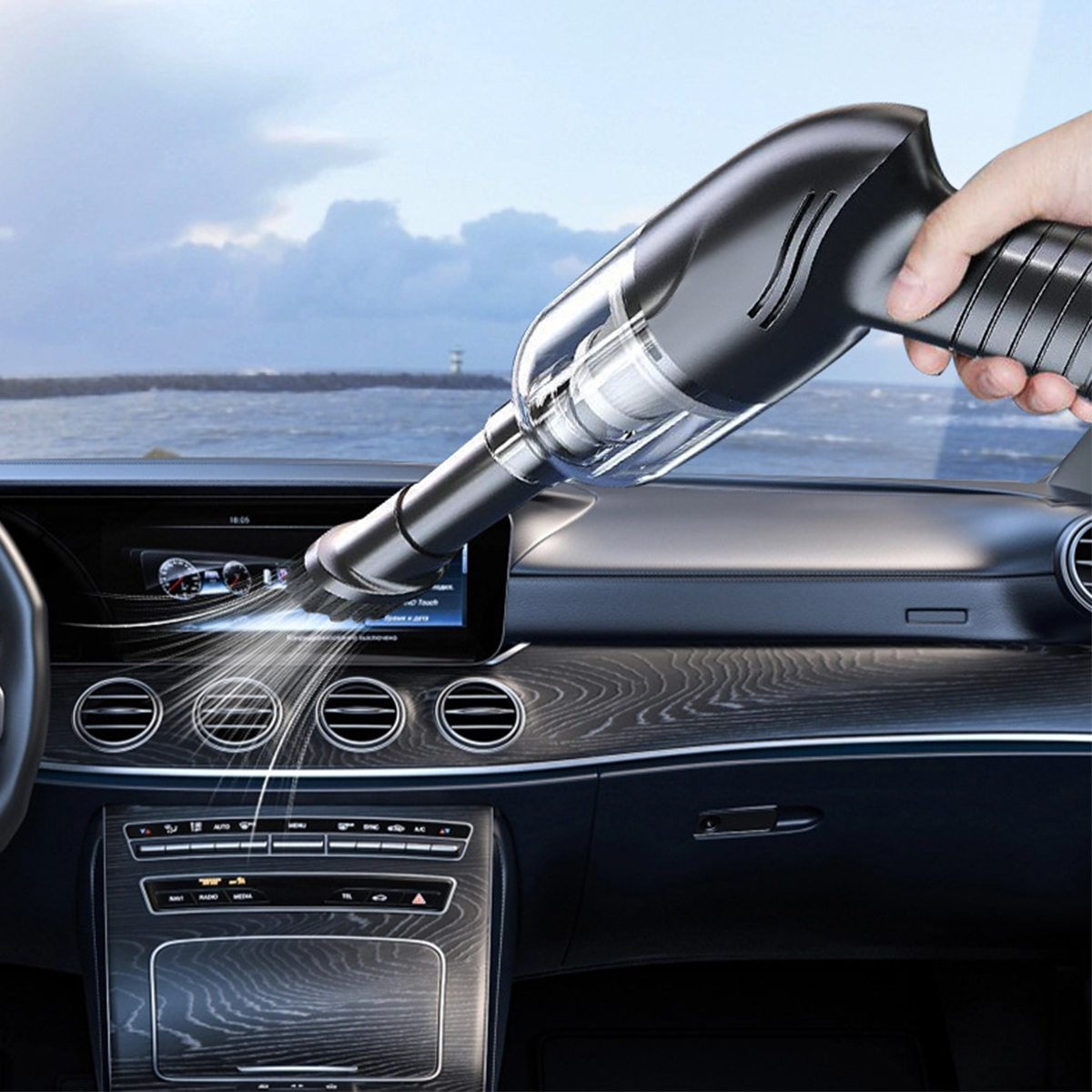 Ein Handstaubsauger saugt das Armaturenbrett eines Autos ab. Zeigt eine saubere Lüftung und einen Innenraum.