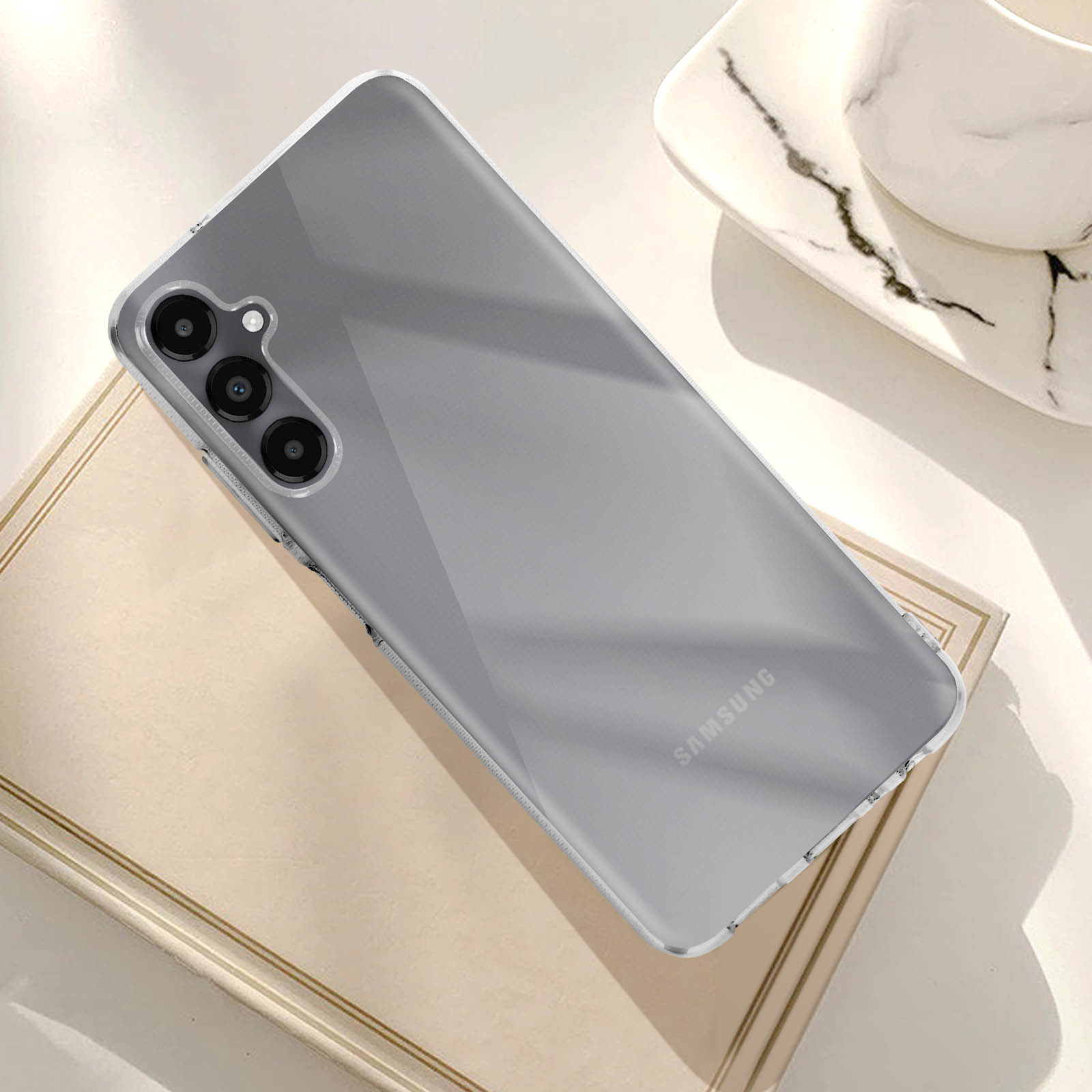 Un telefono in una custodia trasparente su un libro. Il telefono ha tre fotocamere.
