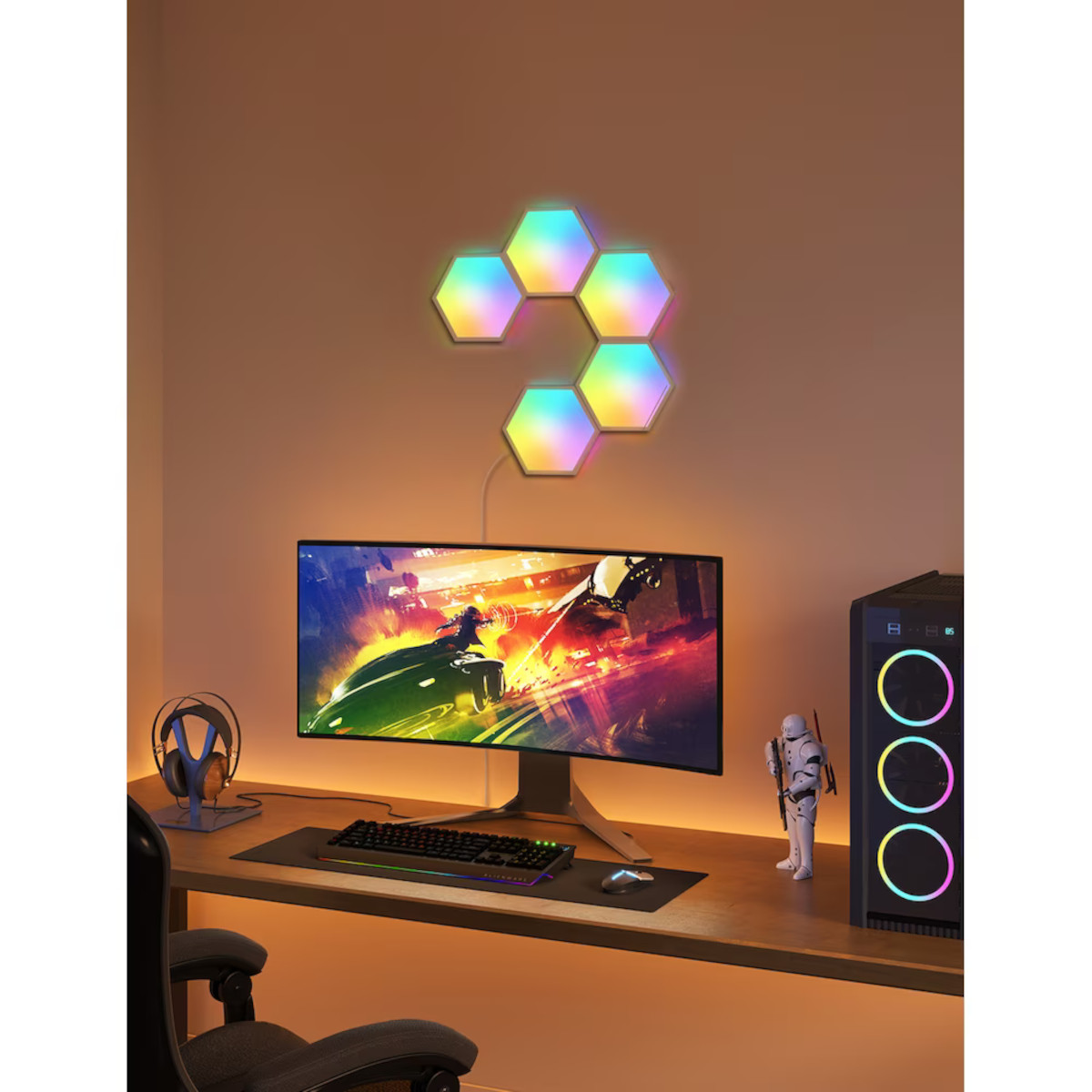 Ein Gamer-Setup mit gebogenem Monitor, bunten Lichtern, Tastatur, Maus und Computer.