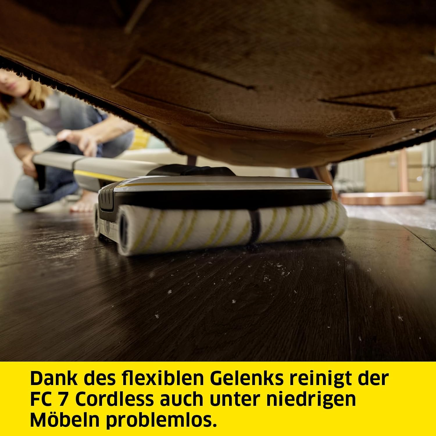Urządzenie czyszczące czyszczące pod meblami, z żółtym tekstem na dole.