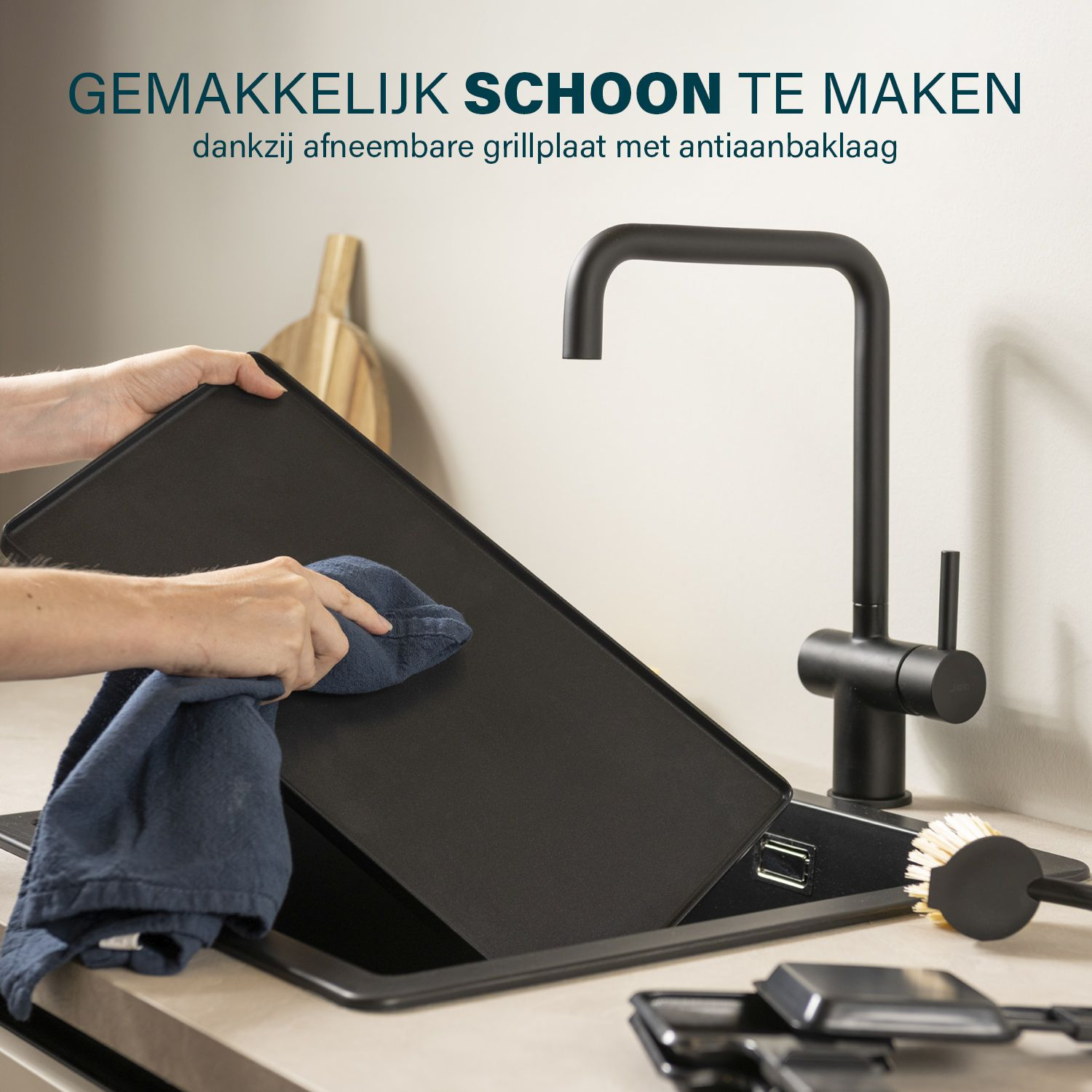 Osoba czyszcząca czarną patelnię. W tle zlewozmywak, kran i szczotka. Tekst: Łatwy do czyszczenia.