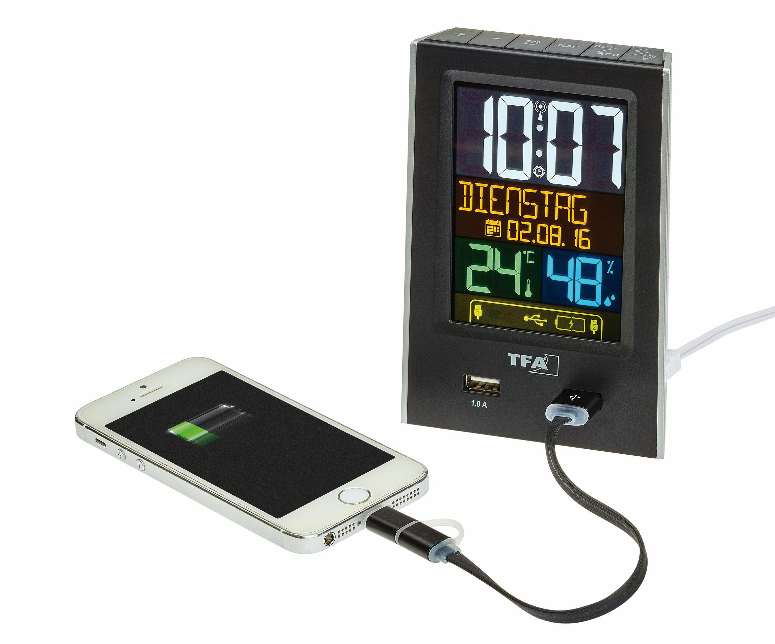Digitaluhr, die ein Telefon auflädt. Die Uhr ist schwarz mit weißem Hintergrund, zeigt Zeit und Datum.
