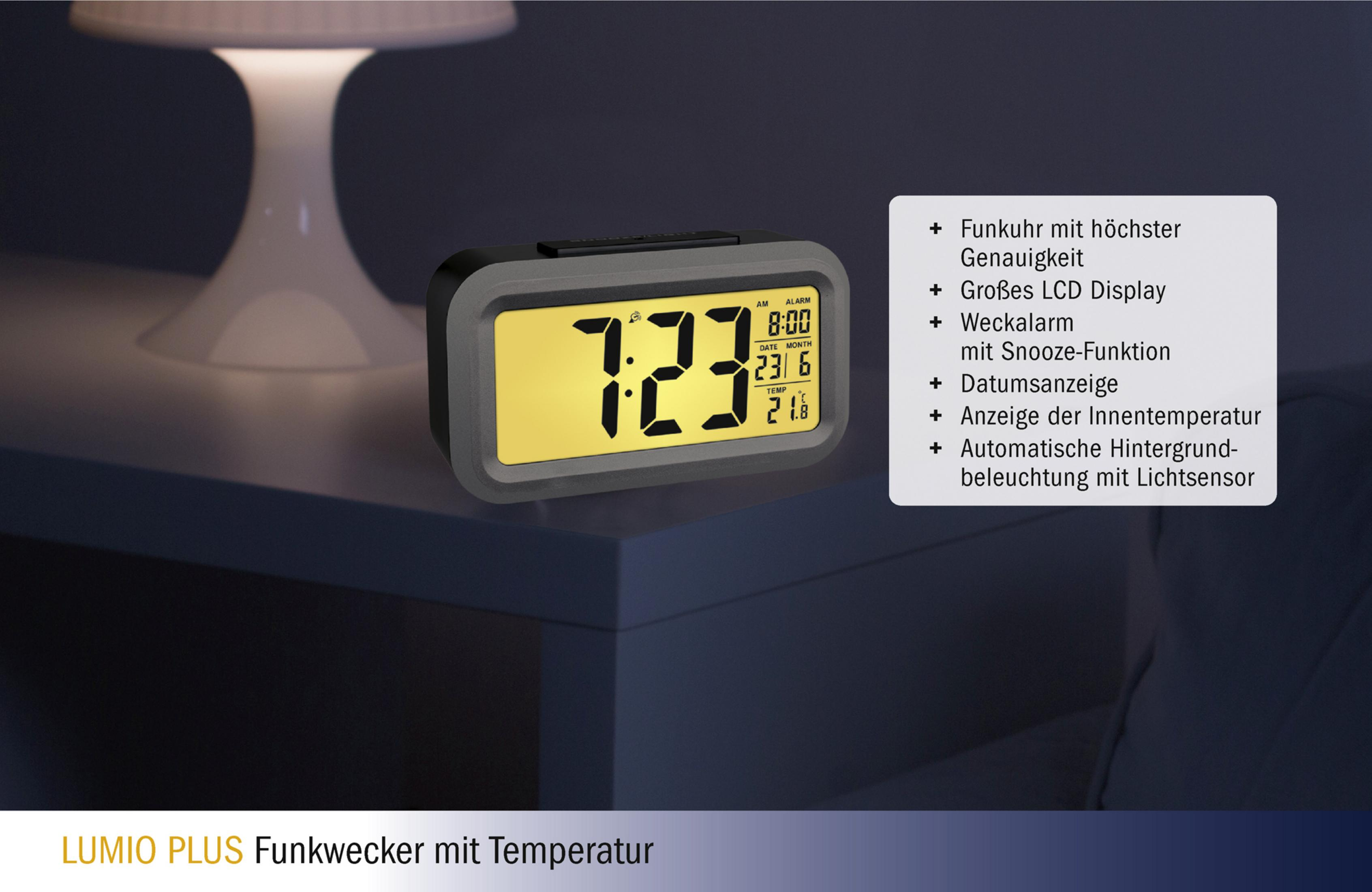 Digitaler Wecker mit gelbem Display, zeigt Zeit und Datum, auf einem weißen Nachttisch.