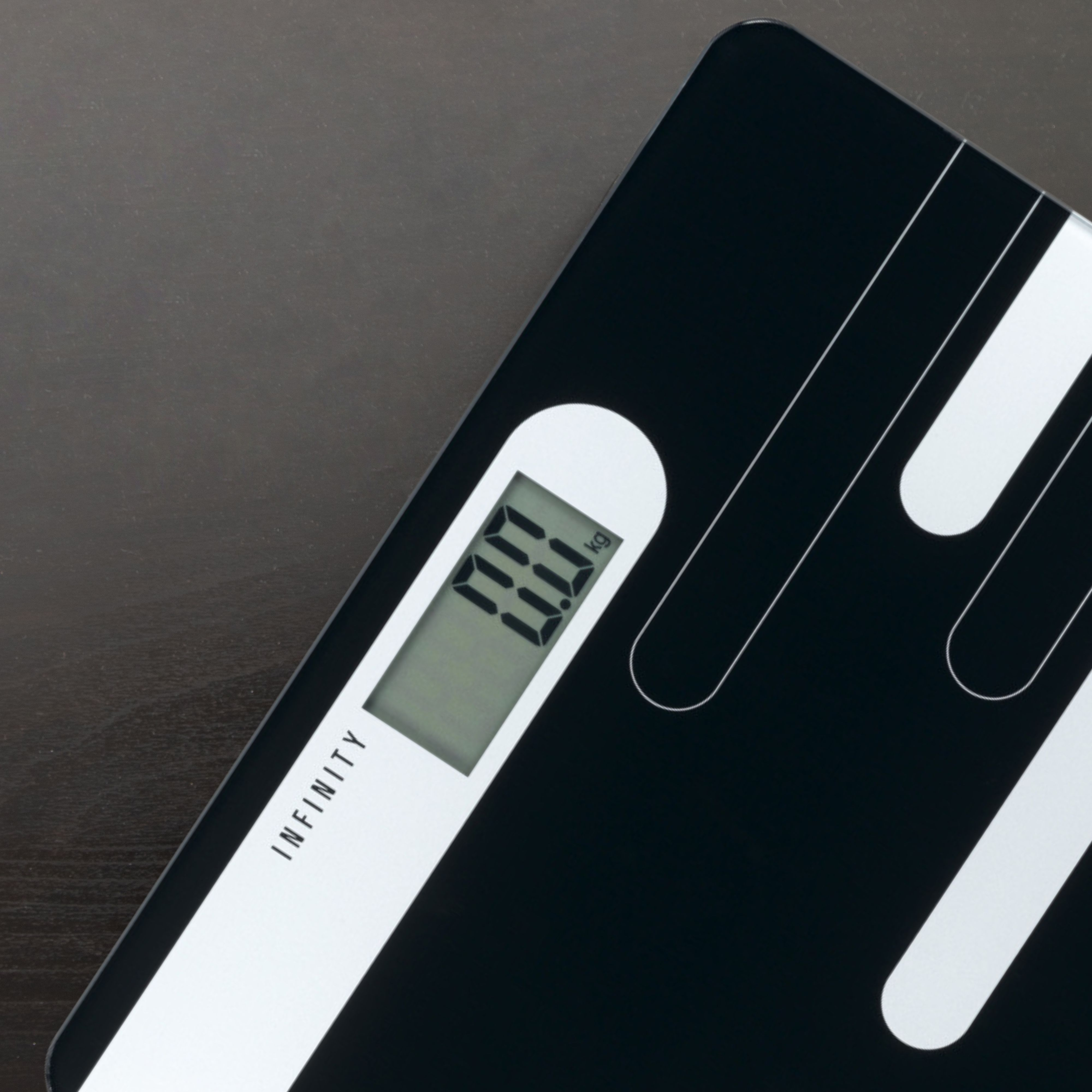 Cyfrowa waga łazienkowa pokazująca 00,0 kg. Czarno-biały design, ciemna drewniana powierzchnia.