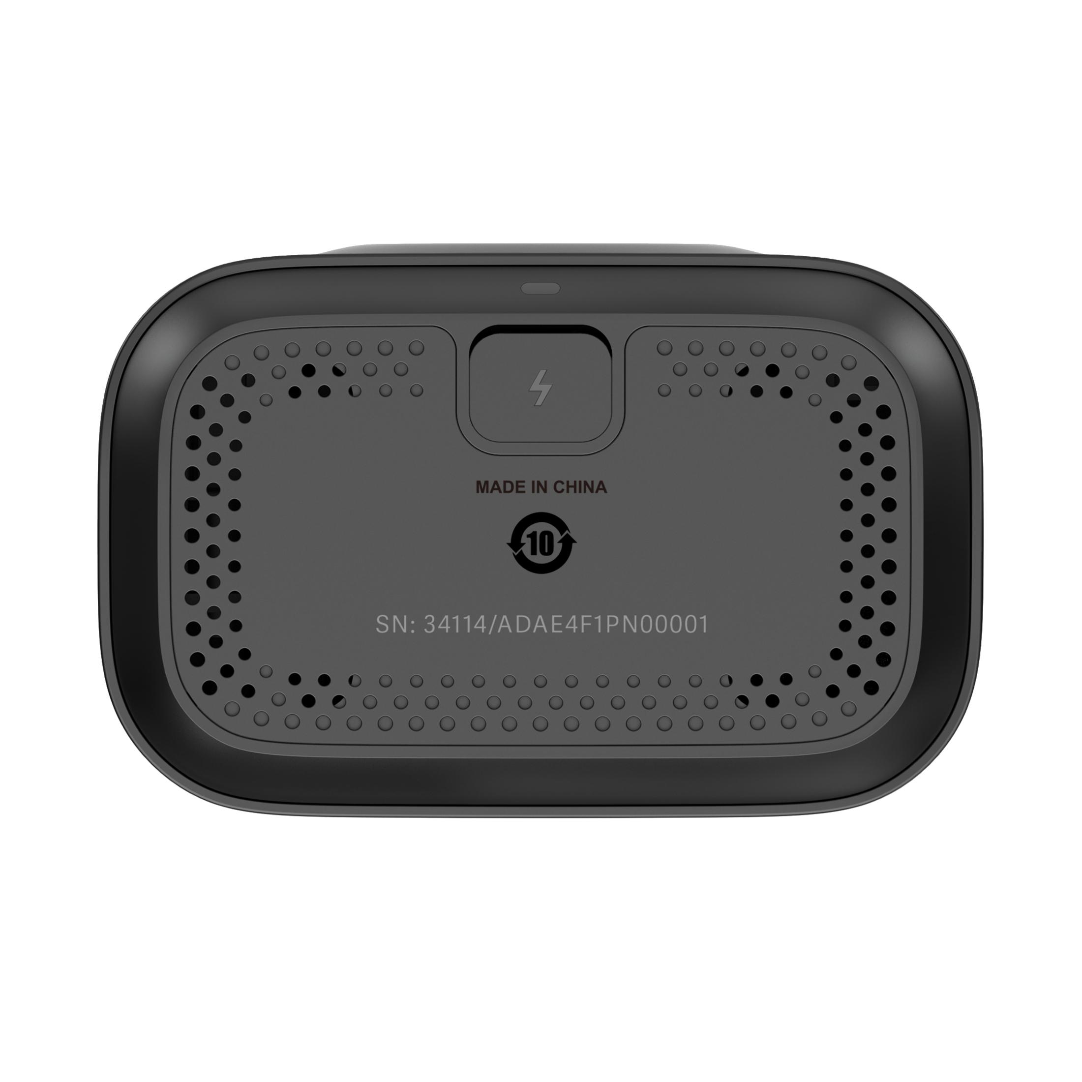 Zwarte onderkant van het apparaat met ventilatiegaten, een symbool voor de oplaadpoort en een serienummer, op een wit oppervlak.