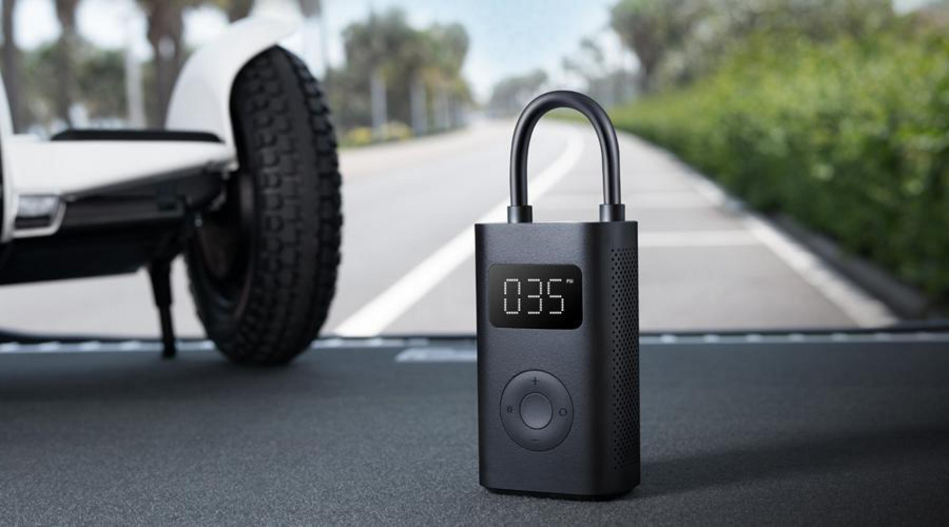 Zwarte luchtpomp op een weg. Een scooterwiel is zichtbaar op de achtergrond.