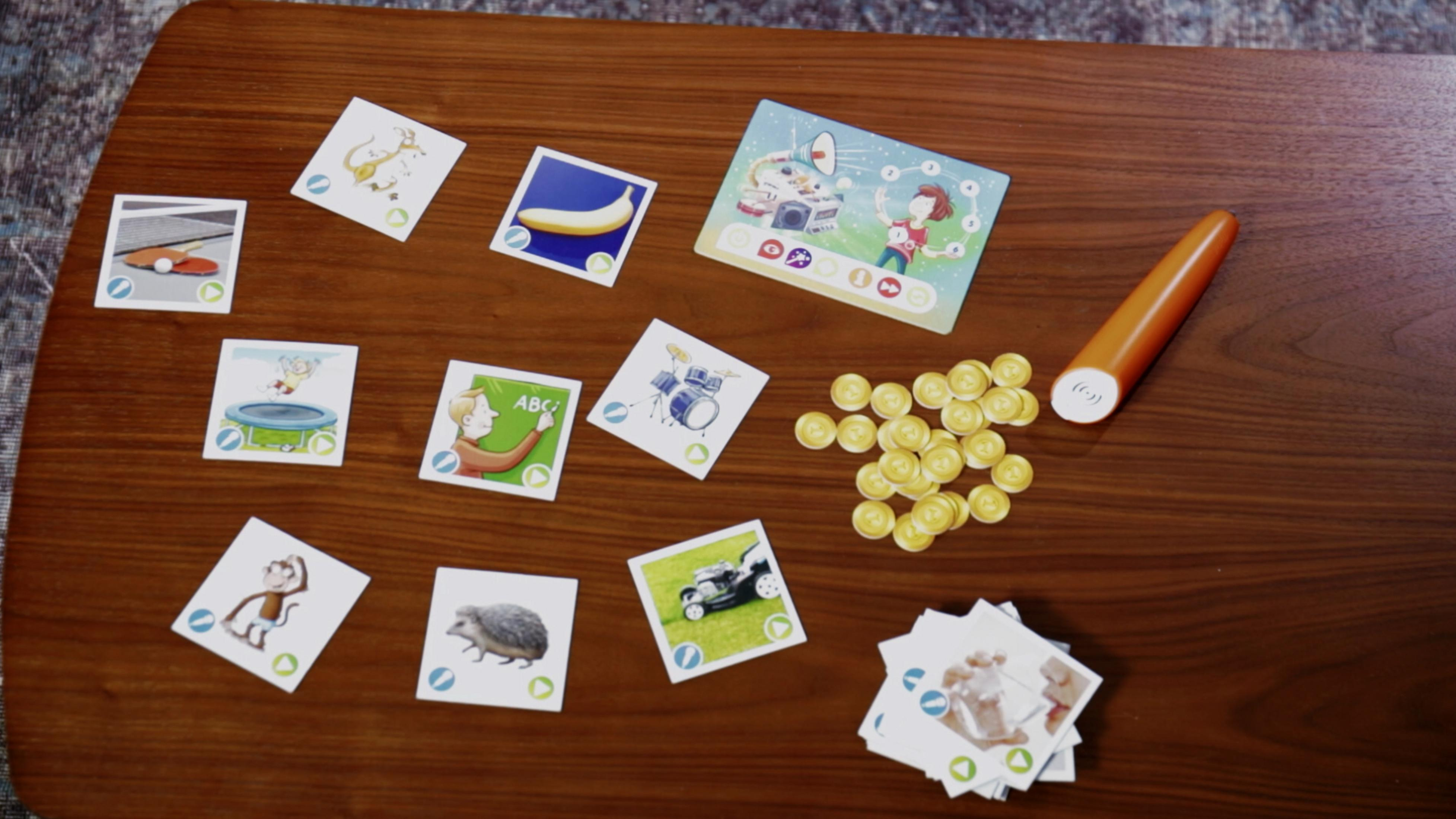 Eine Sammlung von Karten und Spielsteinen auf einem Holztisch. Die Karten haben Illustrationen.