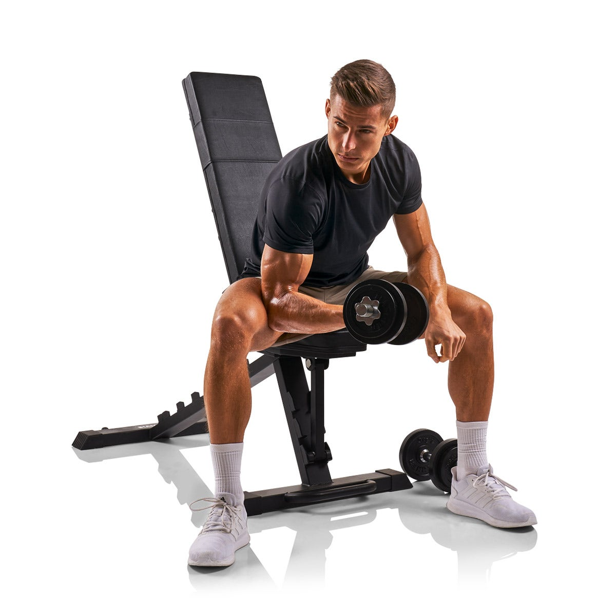 Mann, der eine Hantel hebt, während er auf einer Hantelbank sitzt. Er befindet sich im Fitnessstudio.