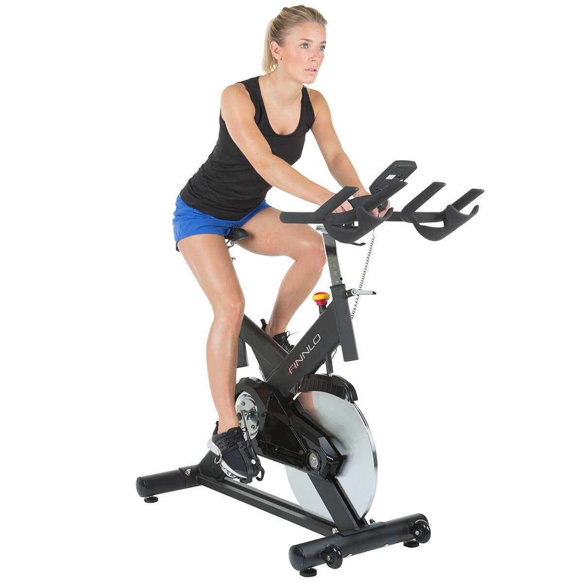 Frau, die auf einem schwarzen stationären Trainingsfahrrad fährt, in einem Fitnessstudio, auf weißem Hintergrund.