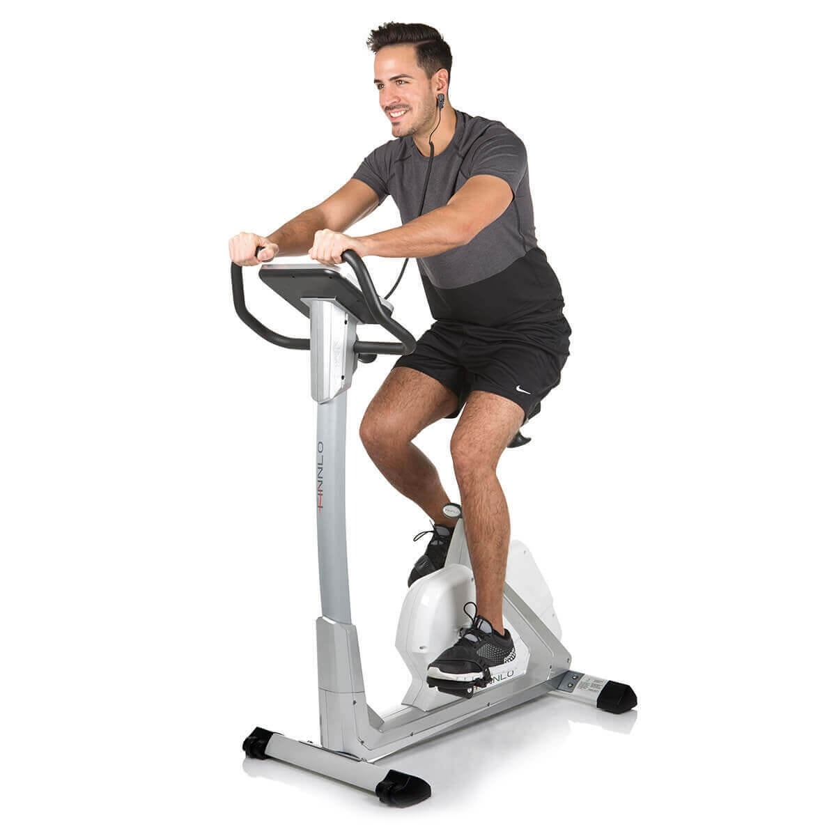 Ein Mann fährt auf einem stationären Trainingsfahrrad, trägt Kopfhörer und Shorts.
