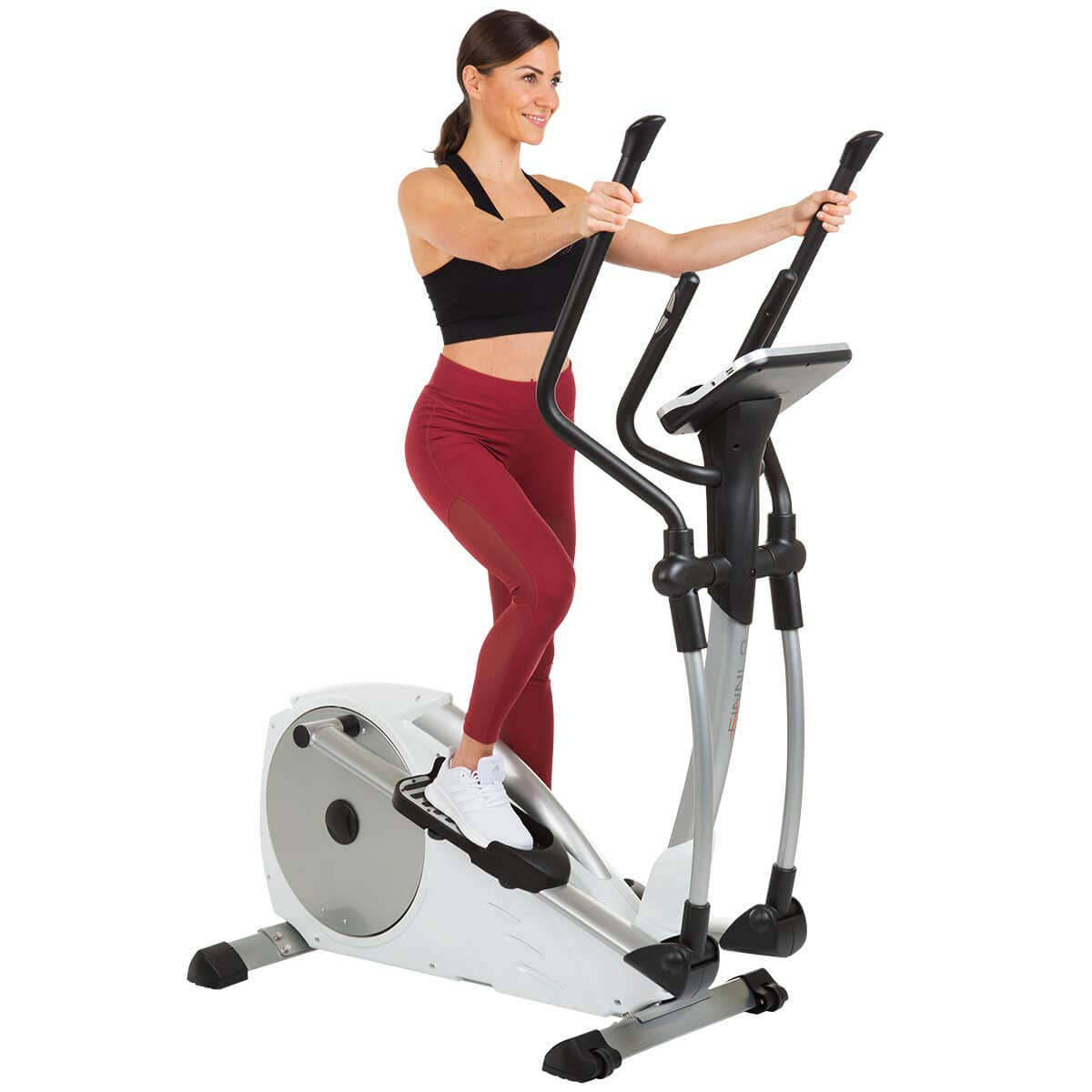 Eine Frau trainiert auf einem weißen und silbernen Crosstrainer. Sie trägt Sportkleidung.
