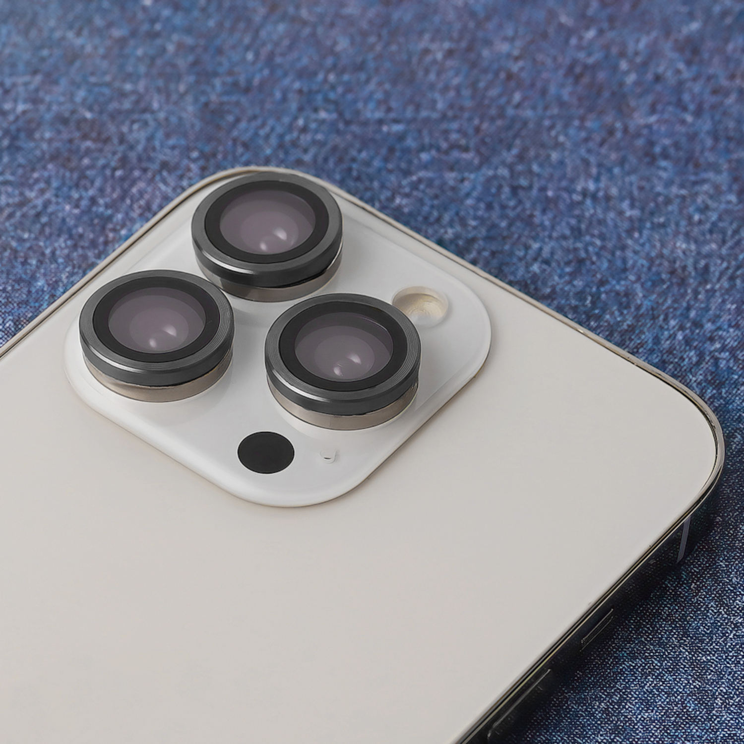 Nahaufnahme eines Telefons mit drei Kameralinsen. Das Telefon ist weiß, die Linsen haben einen dunklen Rand.