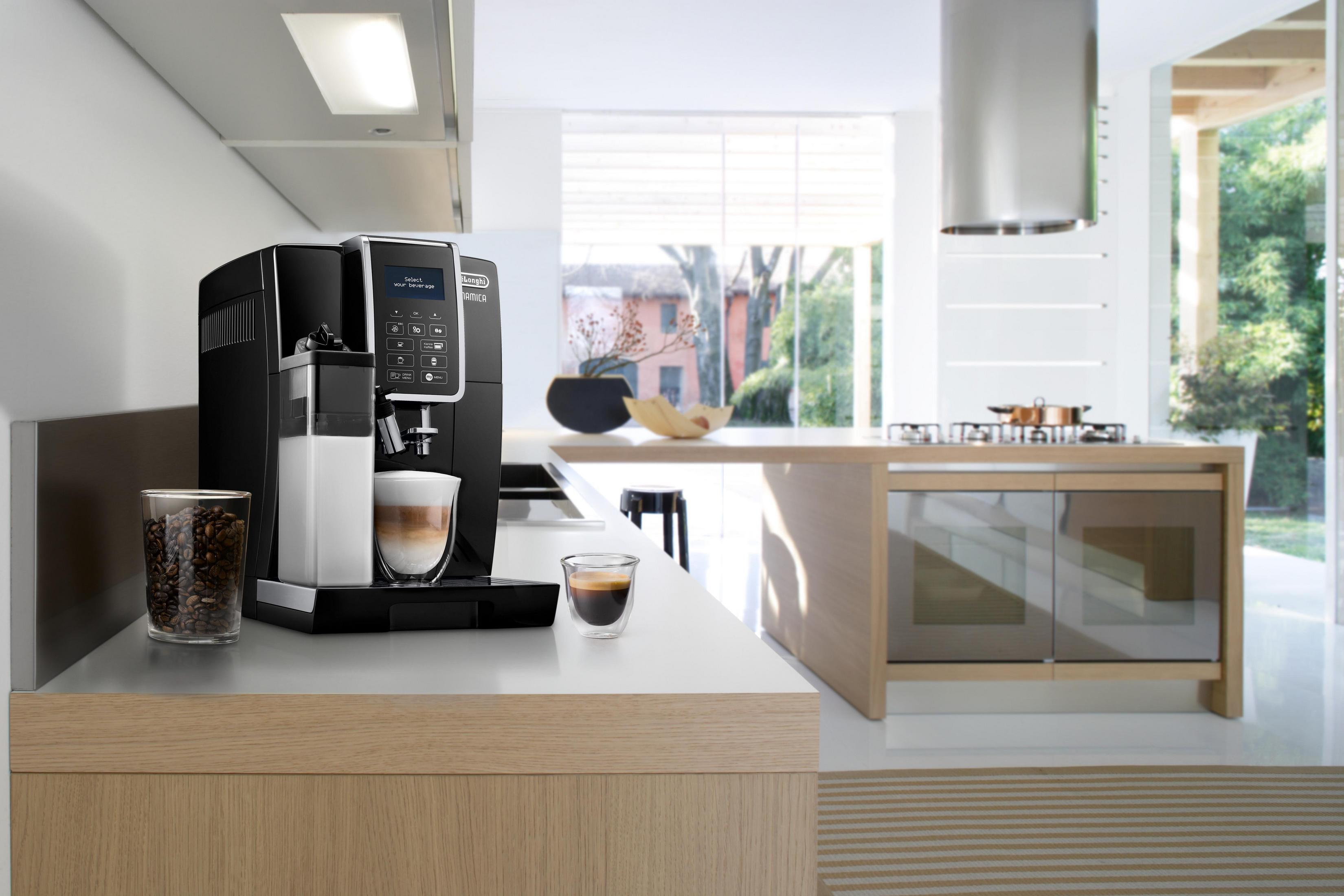Schwarze Kaffeemaschine mit Glas Milch und Kaffee in Küchenumgebung.