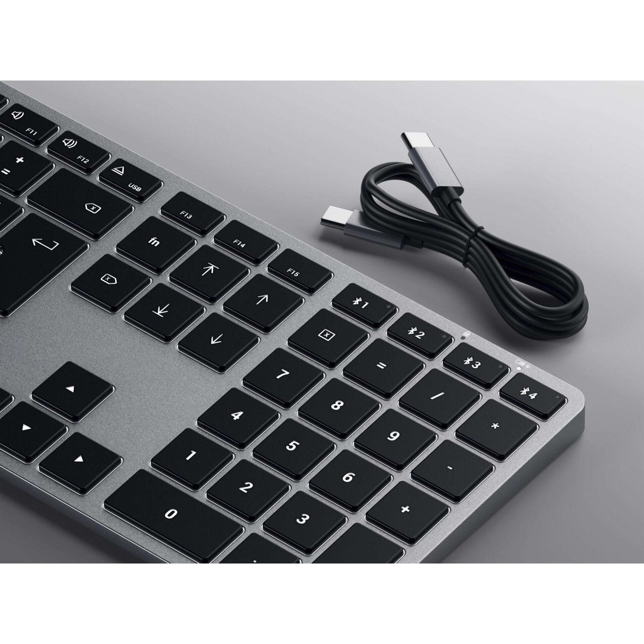 Silberne Tastatur mit schwarzen Tasten und einem schwarzen Kabel auf grauem Grund.