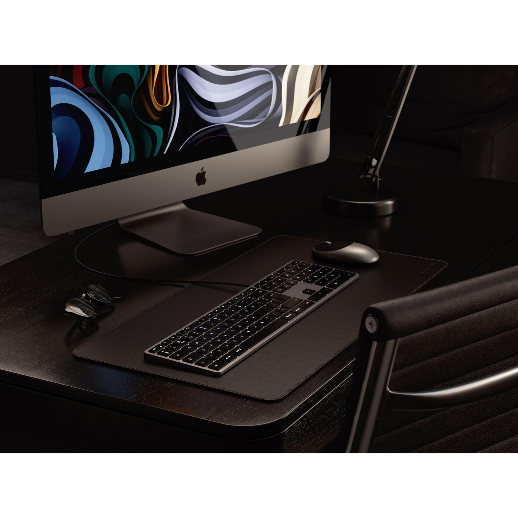 Una scrivania scura con tastiera, mouse, monitor e sedia.