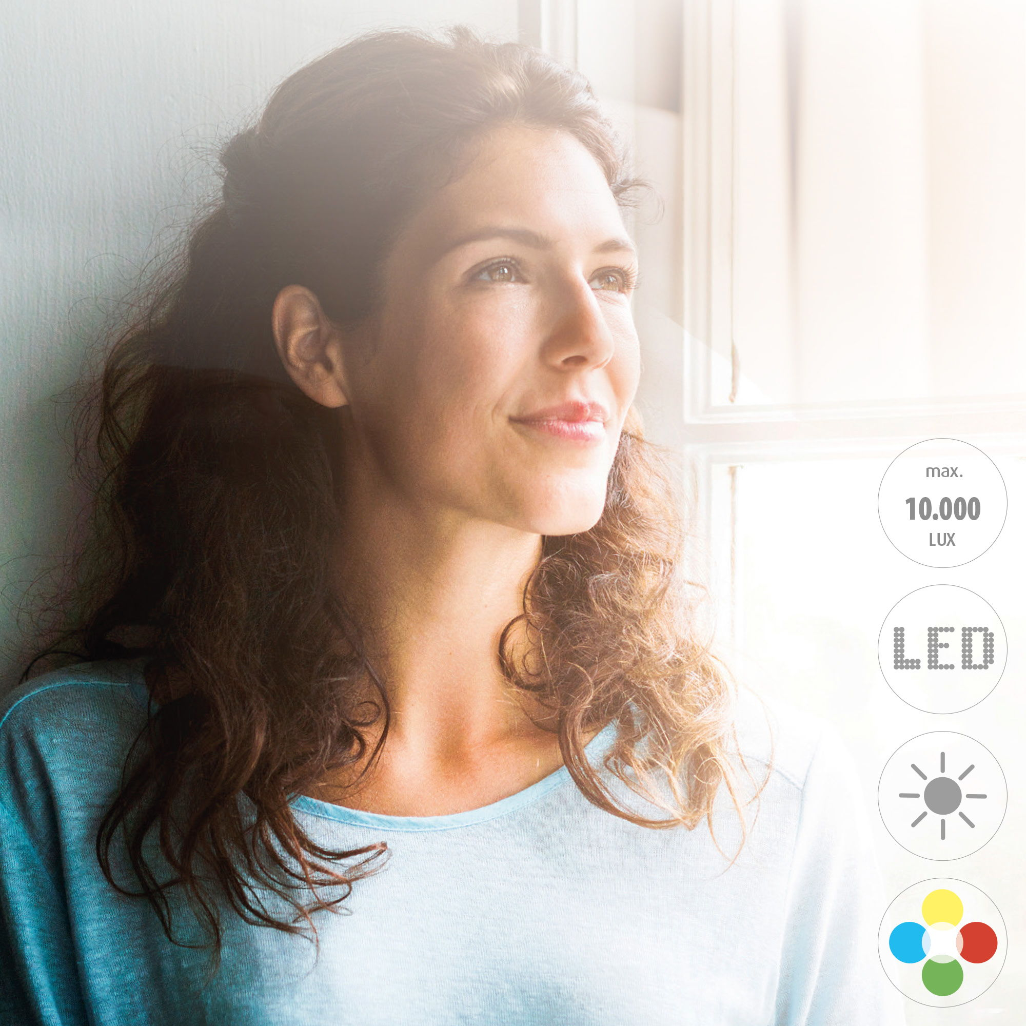 Frau am Fenster, Licht von draußen. Sonnen- und LED-Symbole. Max. 10.000 LUX. Frau blickt nach oben und lächelt.