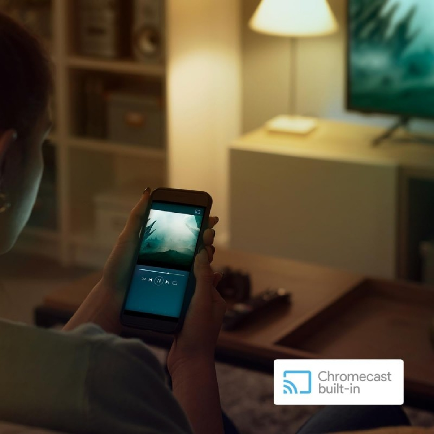 Osoba trzymająca telefon, oglądająca wideo. Logo Chromecast built-in.