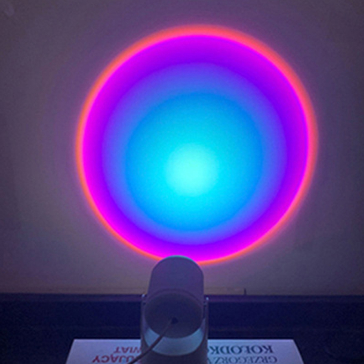 Ein Projektor wirft ein kreisförmiges Licht mit einem lebendigen Farbverlauf aus Pink, Orange und Blau.