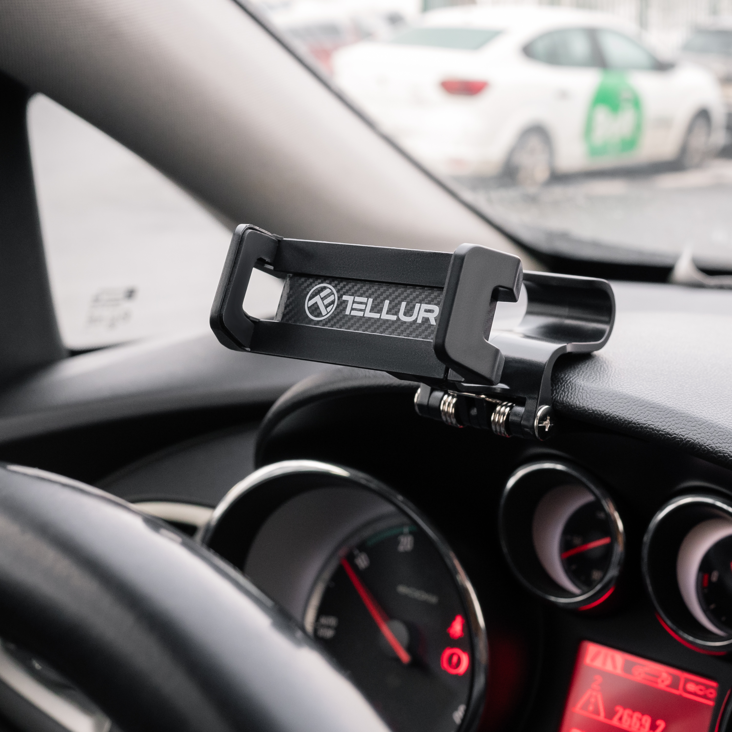 Wnętrze samochodu z uchwytem na telefon przymocowanym do deski rozdzielczej, zasłaniającym widok.