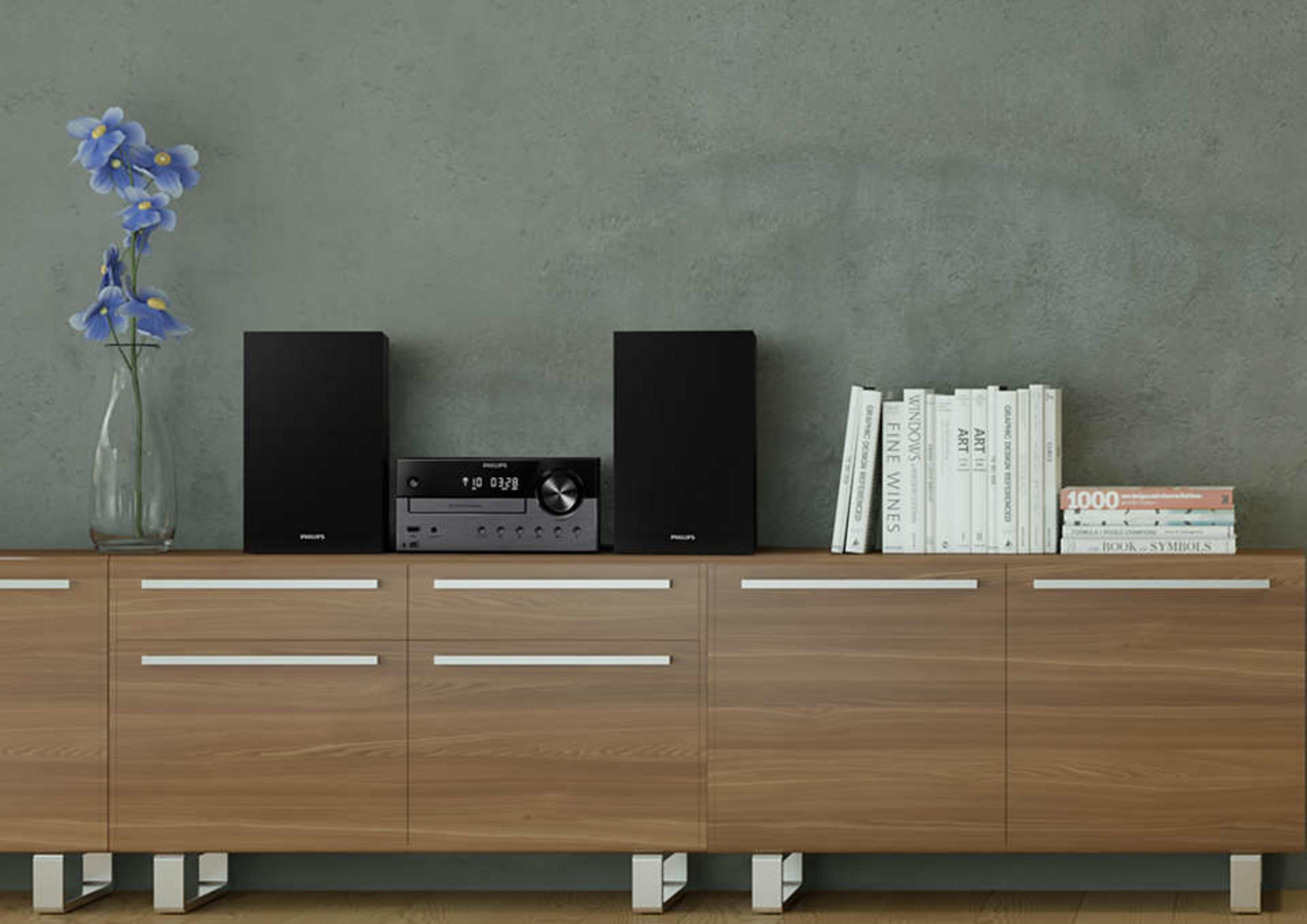 System stereo z czarnymi głośnikami i odtwarzaczem na drewnianej szafce, z książkami i wazonem.