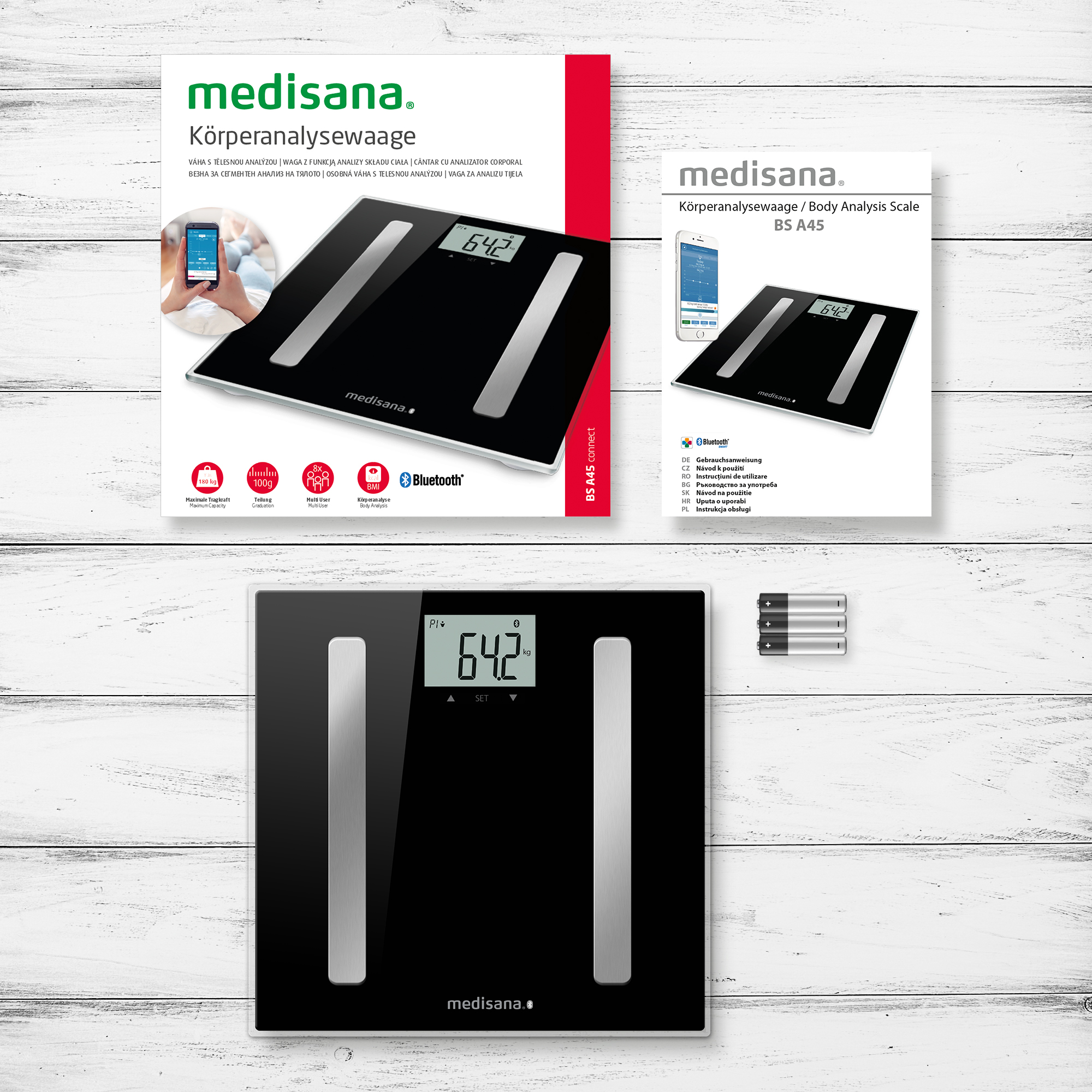 Zwarte lichaamsanalyse weegschaal. Toont 64.2 kg. Doos en handleiding op de achtergrond.