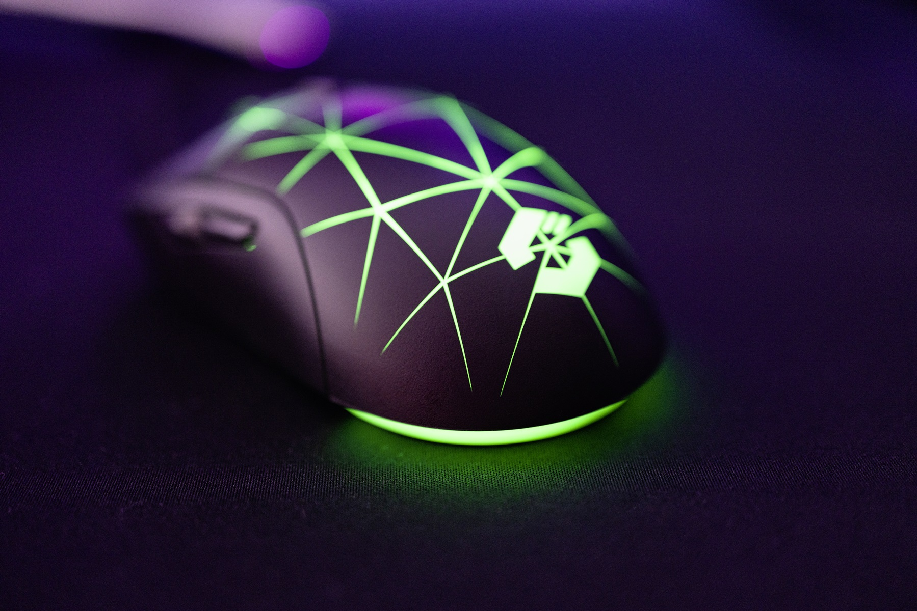 Gaming mouse with green illuminated design on black surface.