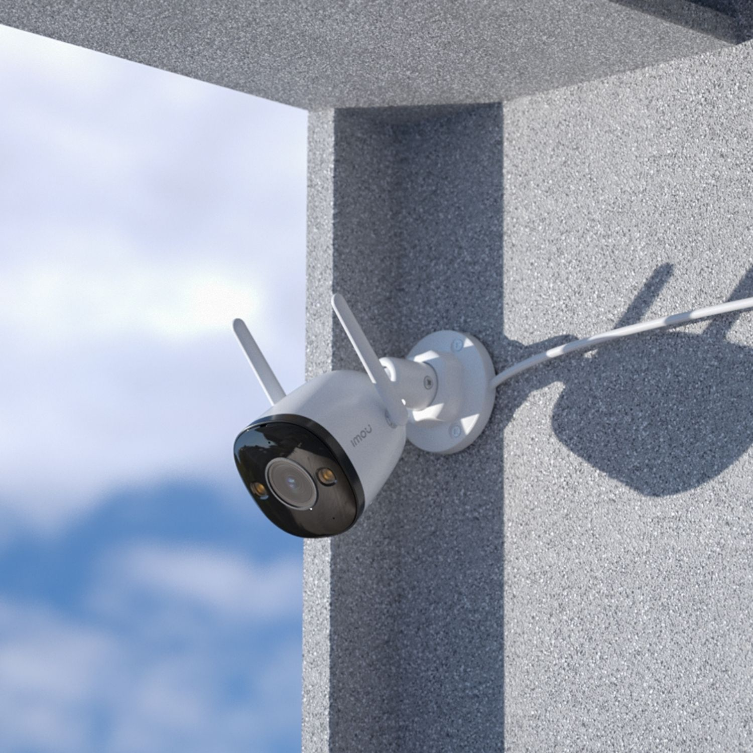 Witte beveiligingscamera voor buiten gemonteerd op een gestructureerde grijze muur, met lucht op de achtergrond.