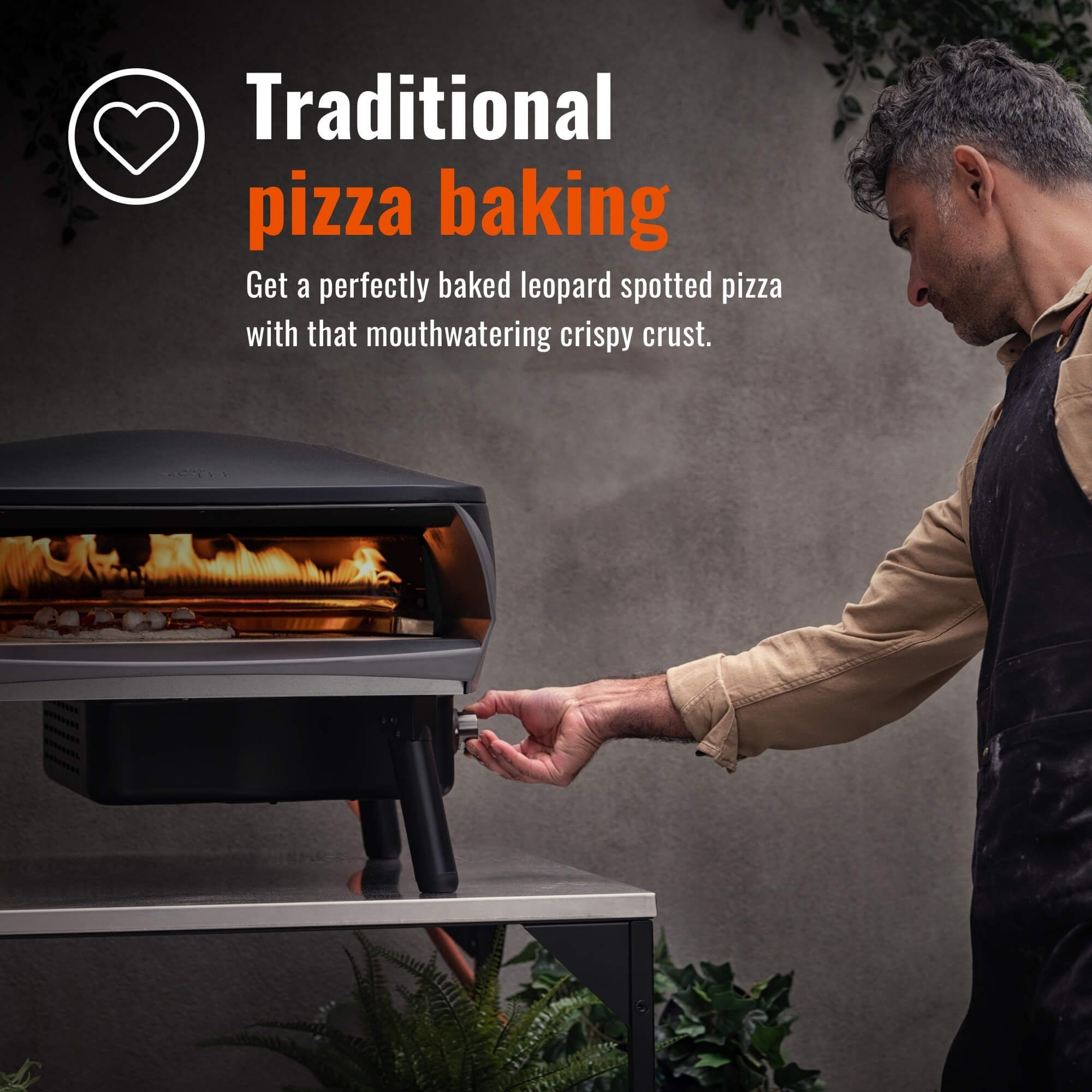 Uomo che cucina la pizza in un forno esterno. Forno grigio, supporto nero e uomo con grembiule. La pizza sta cuocendo.