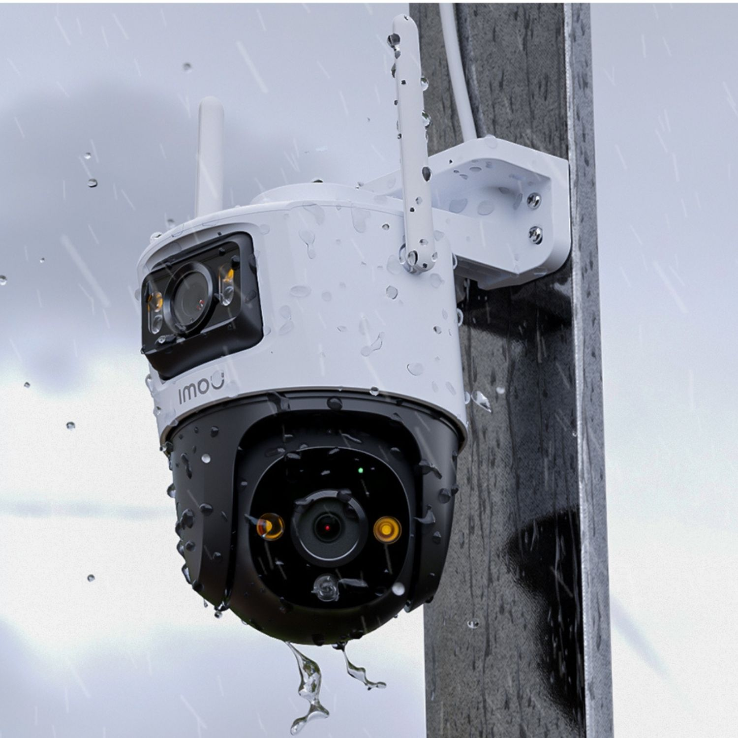 Biało-czarna kamera bezpieczeństwa zamontowana na słupie, widoczne krople wody, z zachmurzonym niebem w tle.