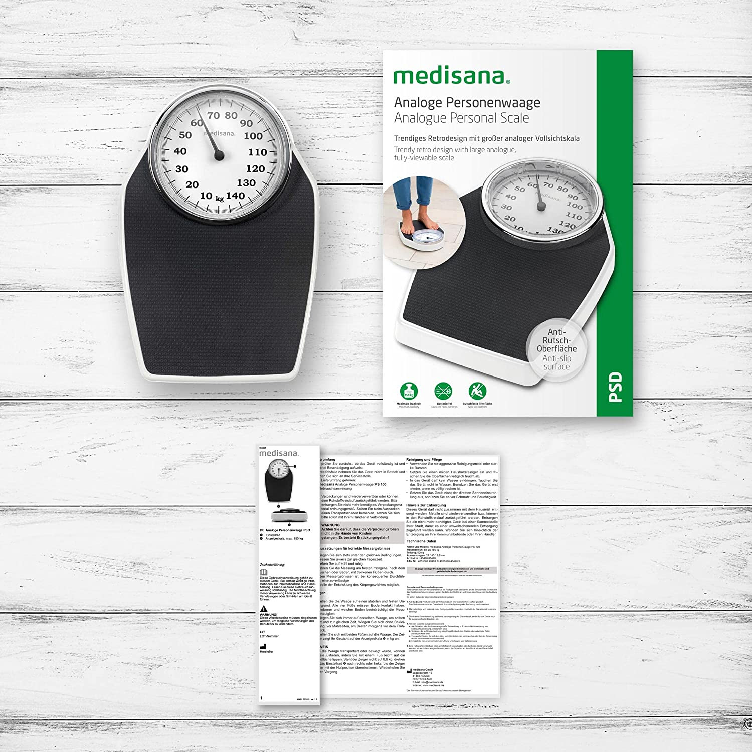 Waga z czarno-białą tarczą. Opakowanie produktu i broszura znajdują się obok wagi.