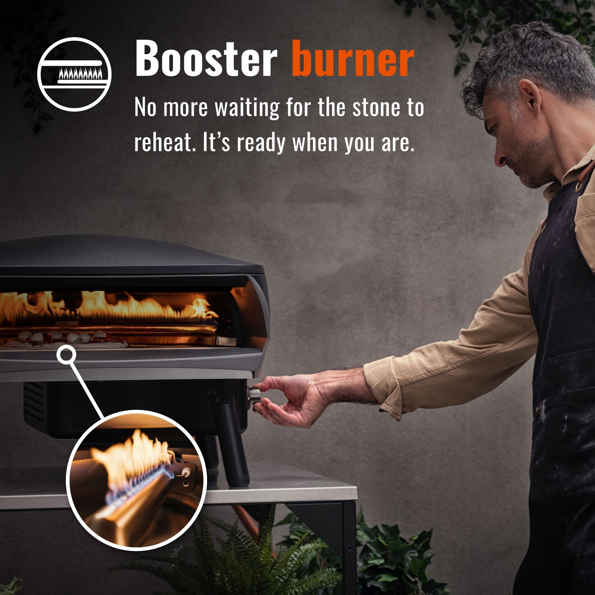Uomo che usa un forno per pizza all'aperto. Fiamma accesa all'interno. Tavolo in acciaio inox.