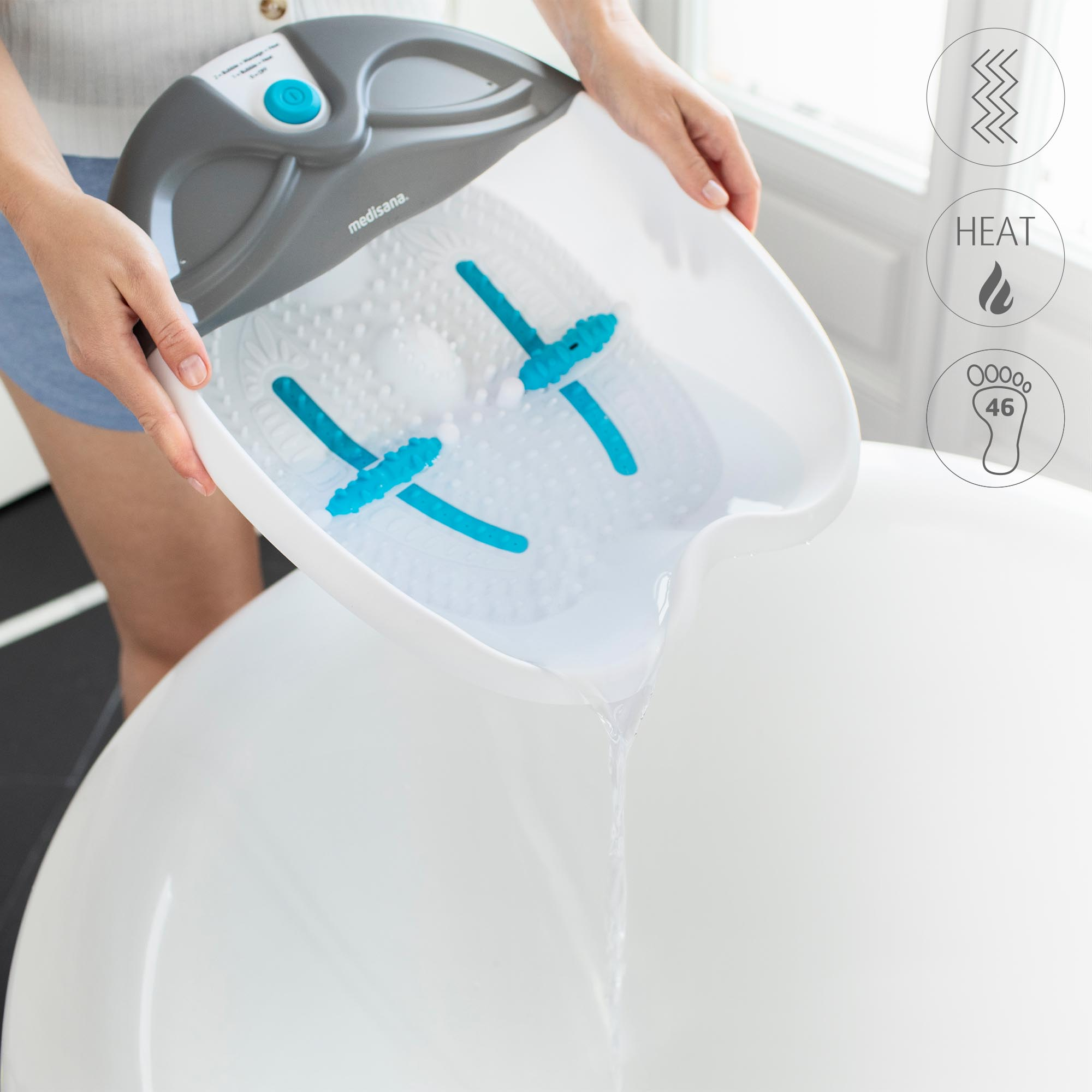 Manos sosteniendo un spa de pies blanco vertiendo agua en una bañera blanca.