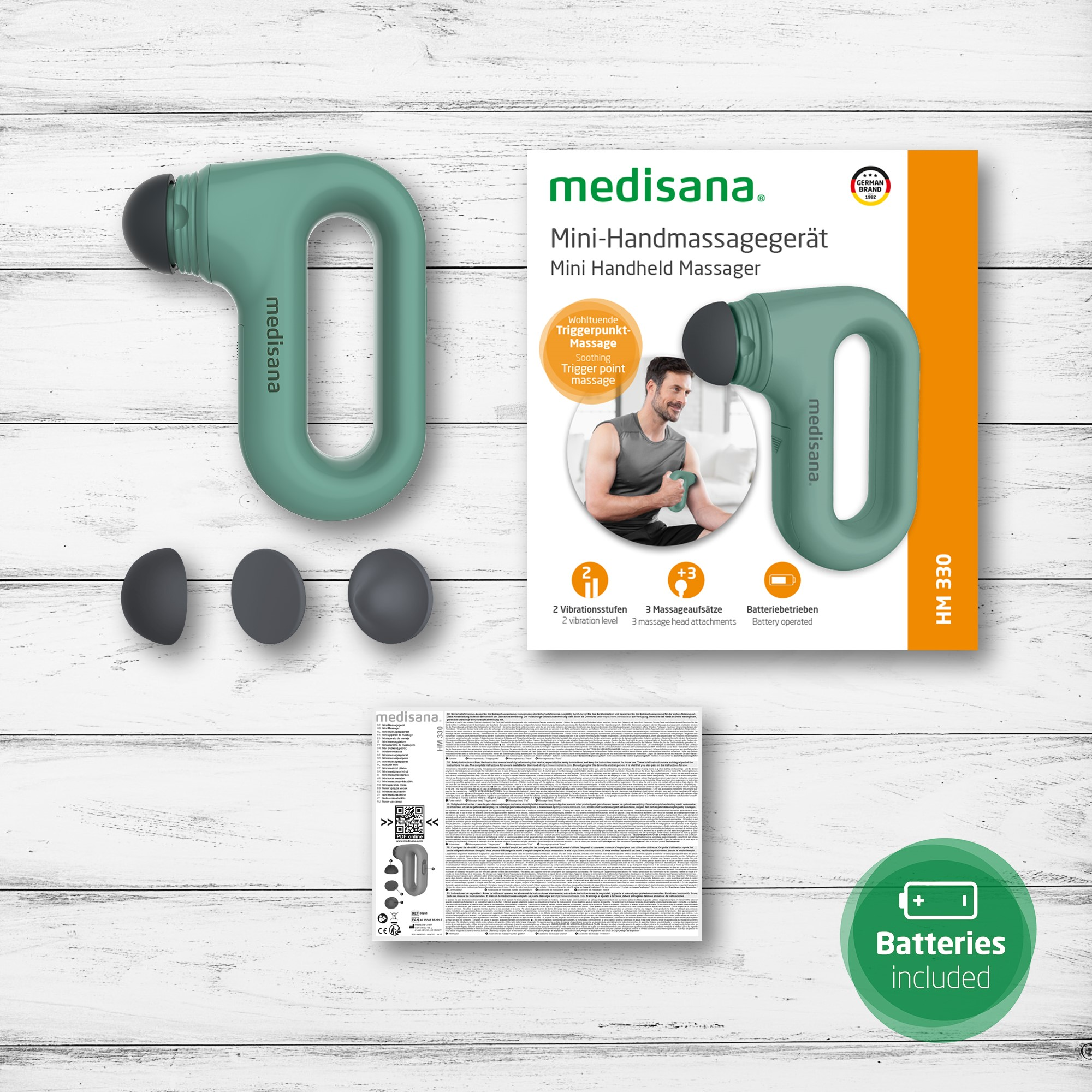 Handmassagegerät-Set. Grünes Massagegerät, 3 Aufsätze und Verpackung mit Text und Diagrammen.