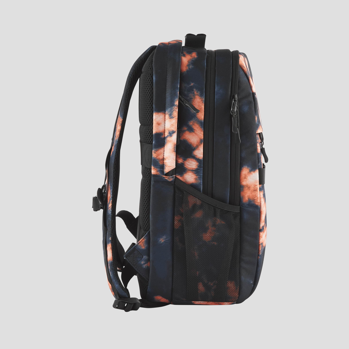 Mochila con estampado tie-dye sobre un fondo gris claro. Vista lateral de la mochila.