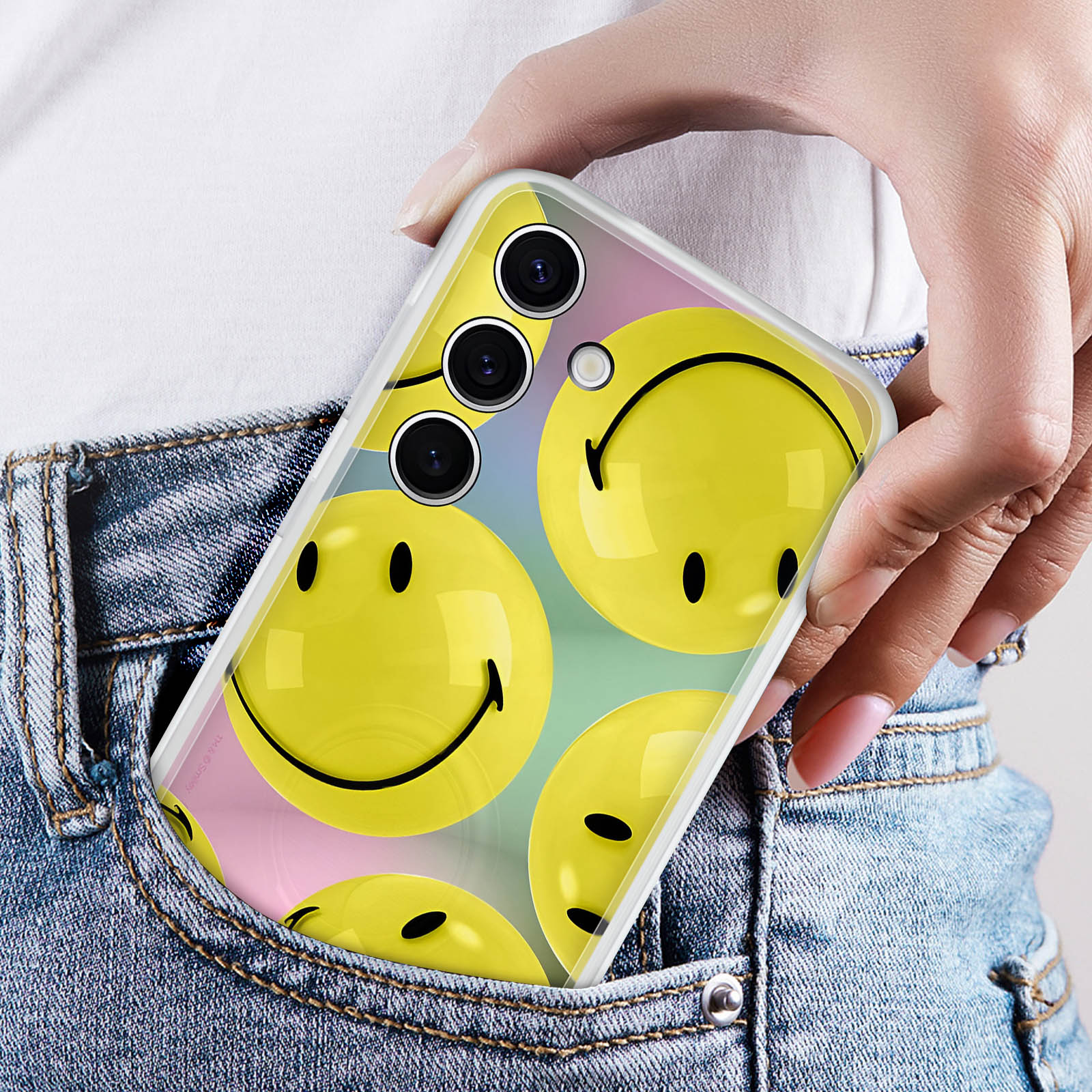 Ręka w kieszeni trzymająca etui na telefon z uśmiechniętymi buźkami.