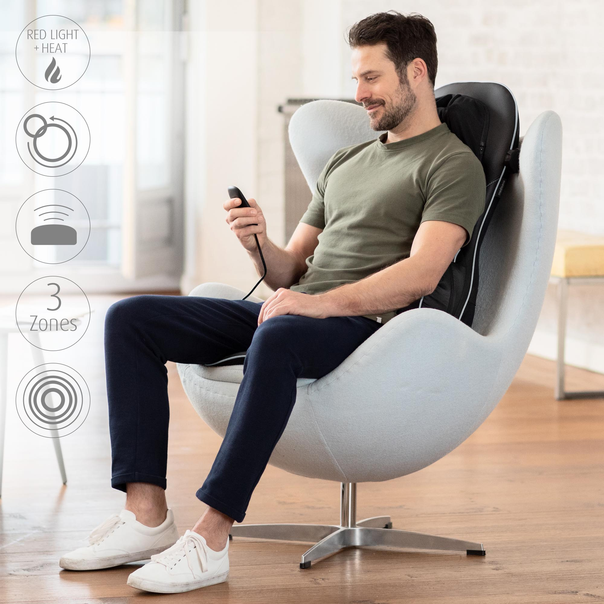 Mężczyzna siedzi na krześle używając masażera pleców.