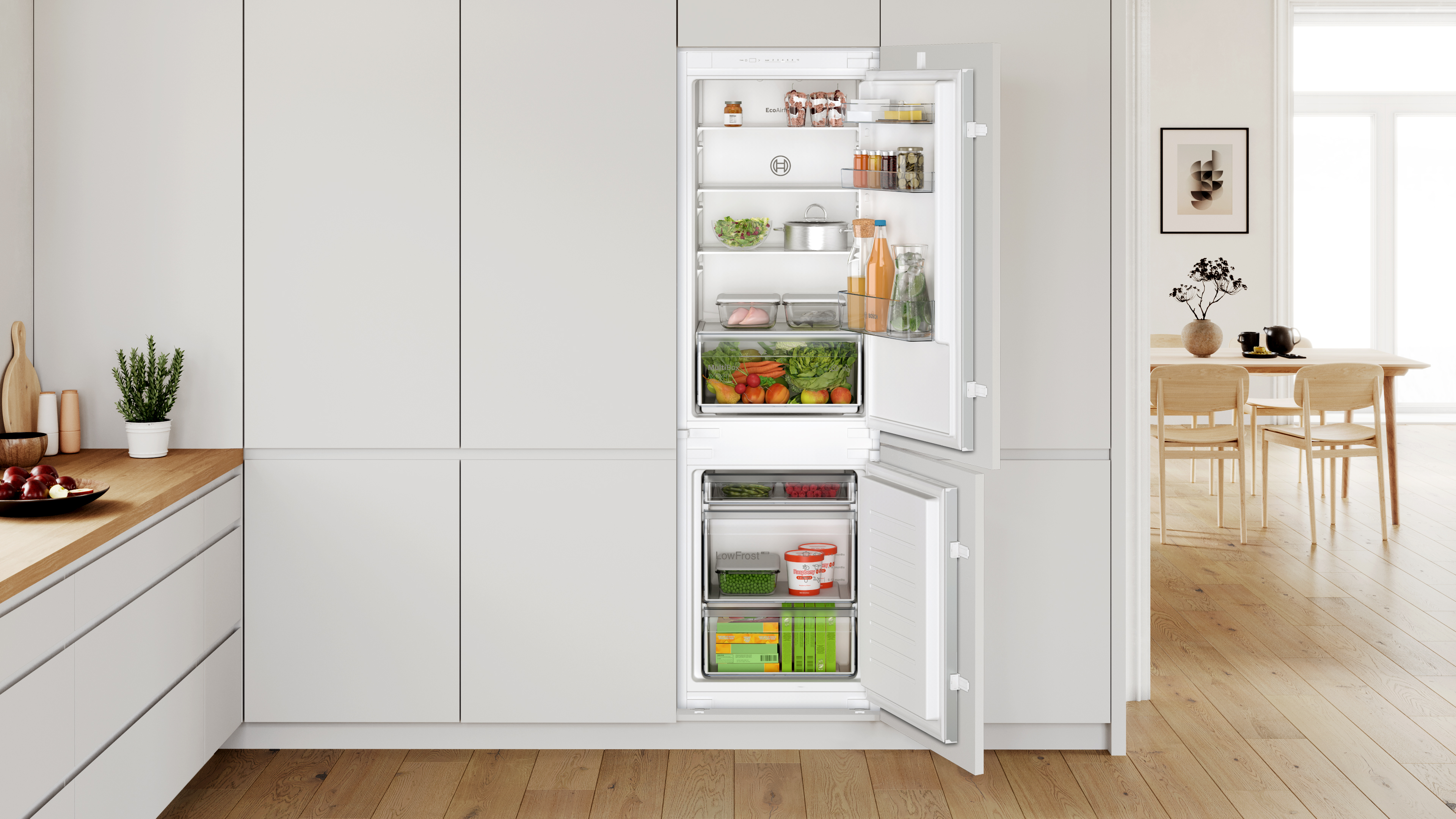 Cucina moderna con frigorifero aperto, cibo, armadi bianchi e banconi in legno.