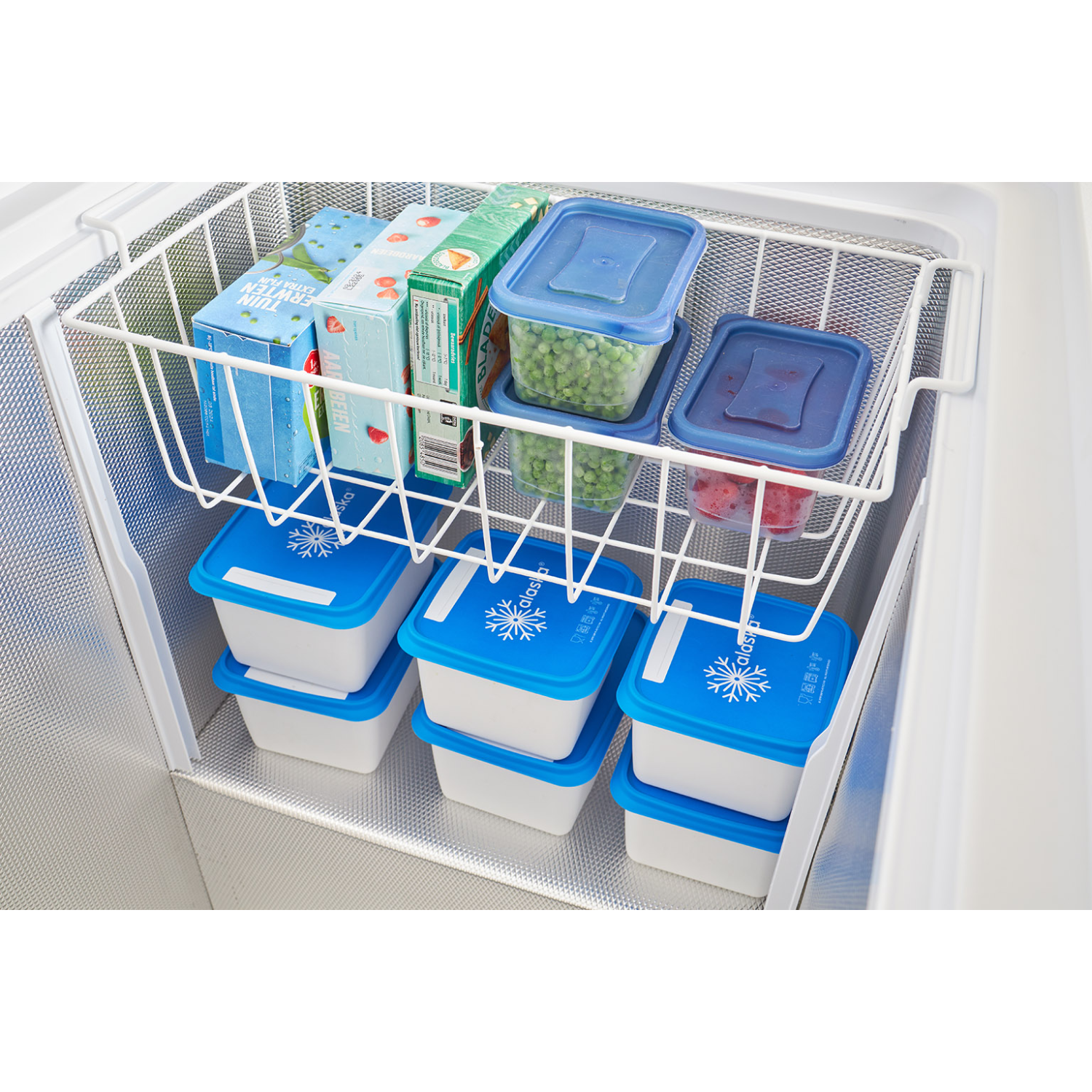 Congelatore con cibi surgelati in contenitori e scatole. Mensola in filo bianco e contenitori blu.