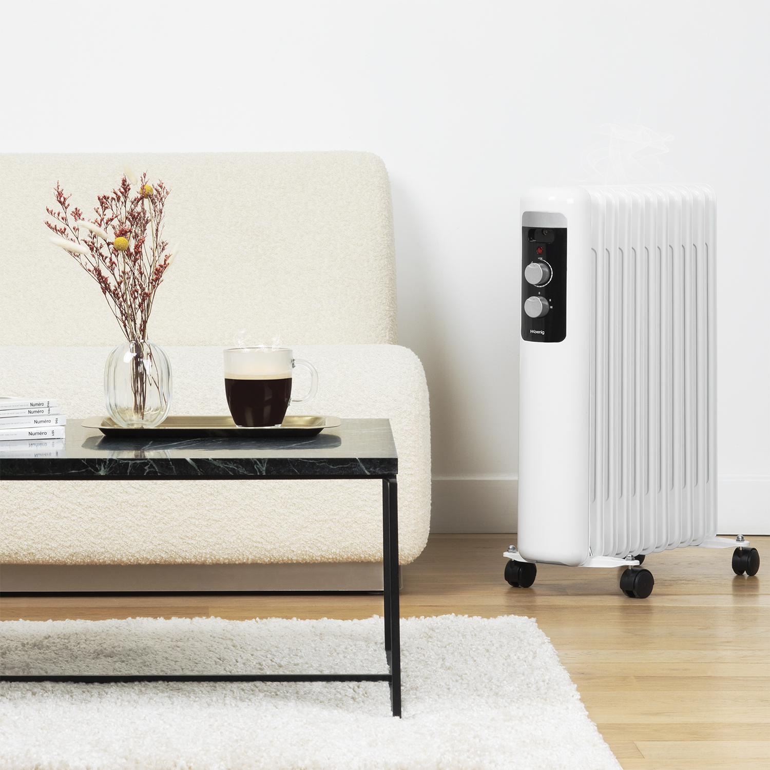 Un termosifone elettrico bianco, tavolino, divano e vaso di fiori in una stanza.