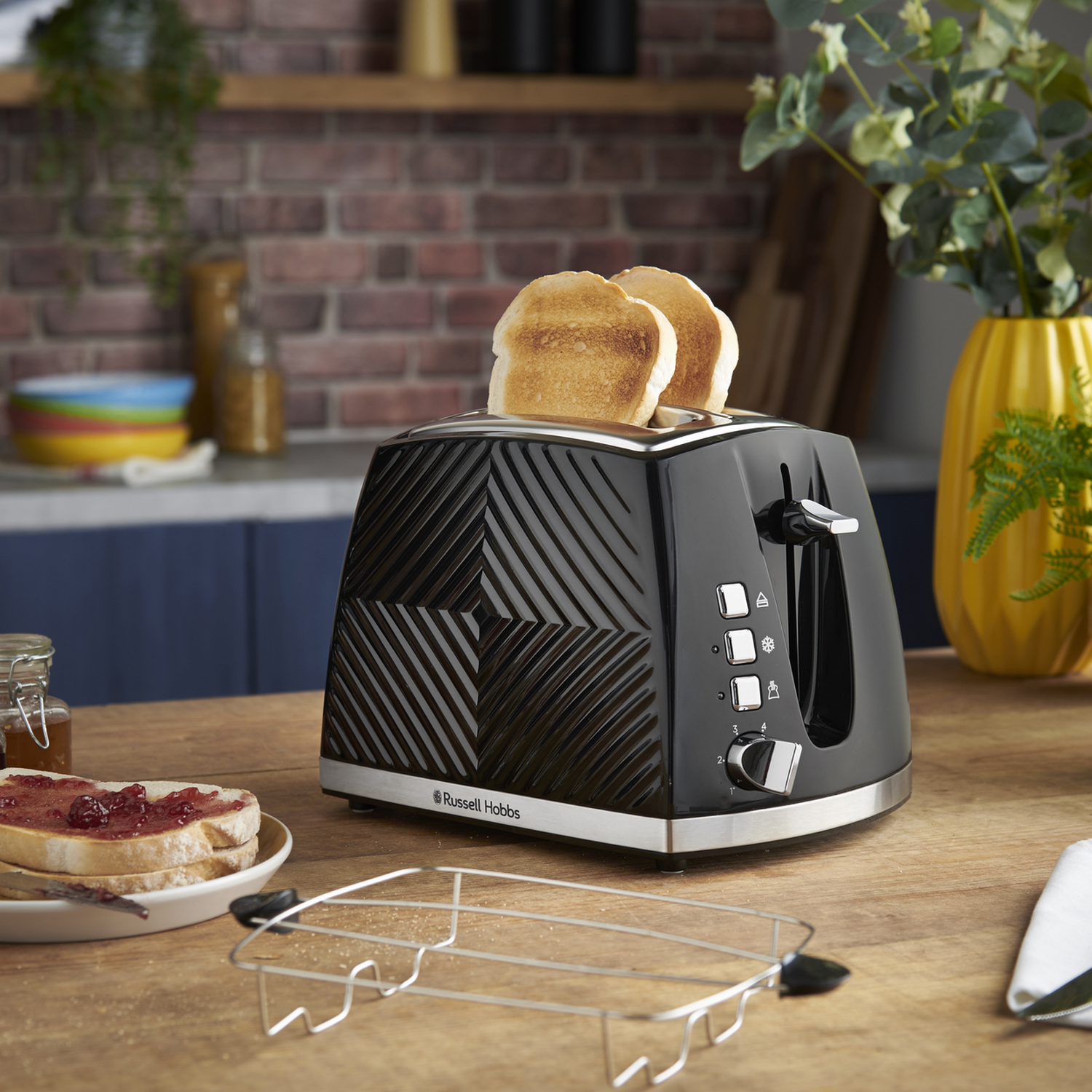 Schwarzer Toaster mit zwei Toastscheiben. Toastscheiben mit Marmelade auf dem Tisch und ein kleiner Ständer.