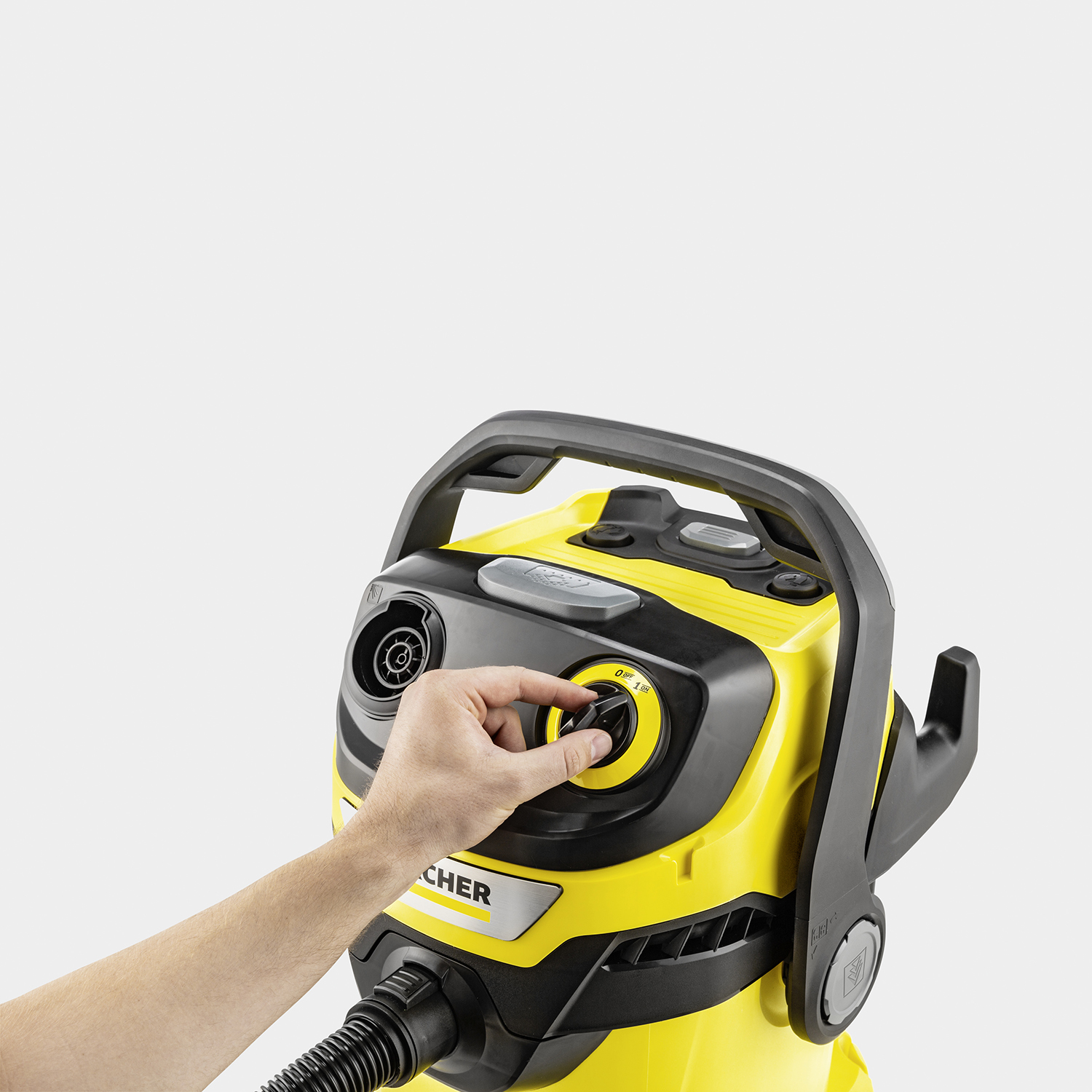 Ręka obraca pokrętło na żółtym odkurzaczu.