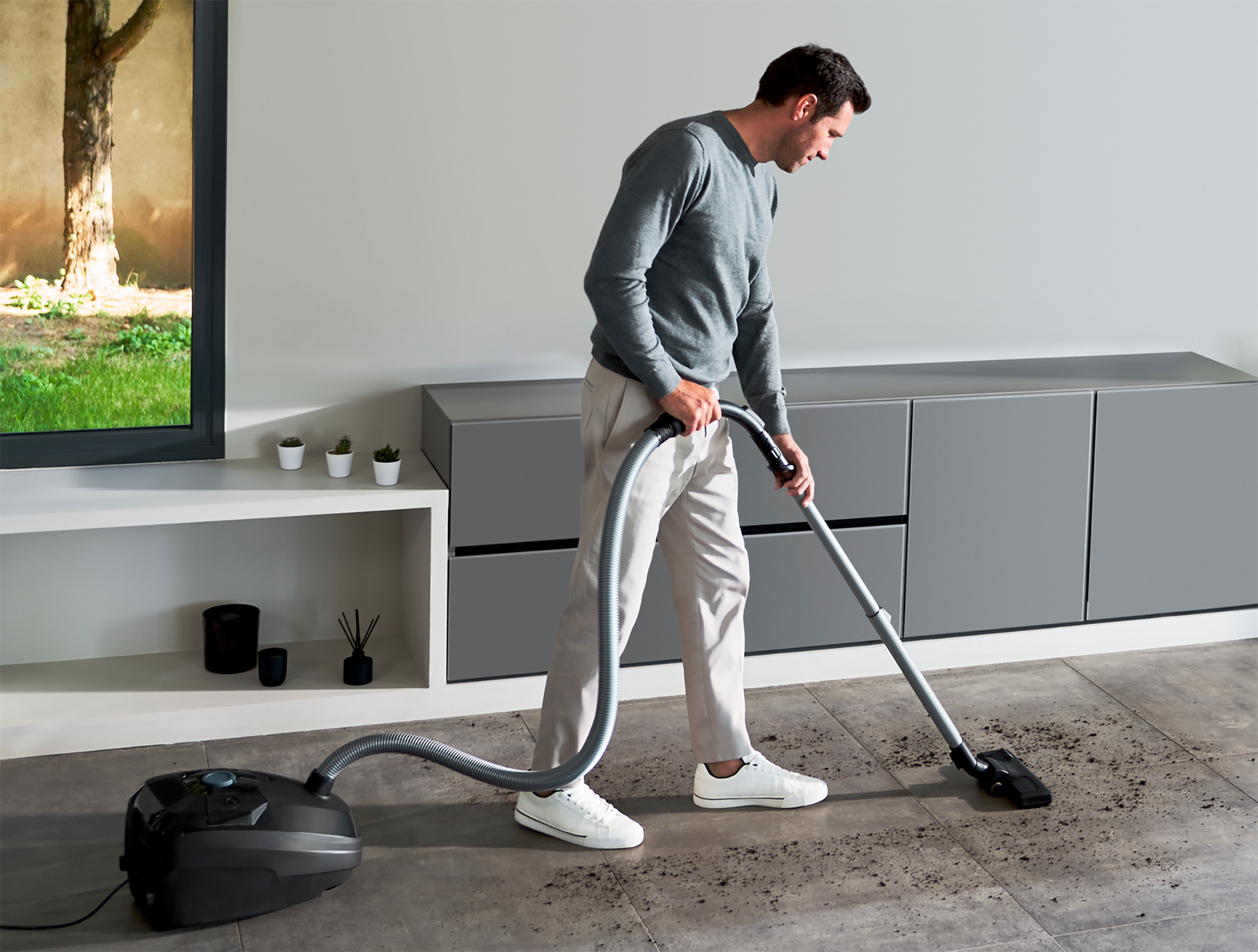 Mężczyzna odkurzający podłogę odkurzaczem.