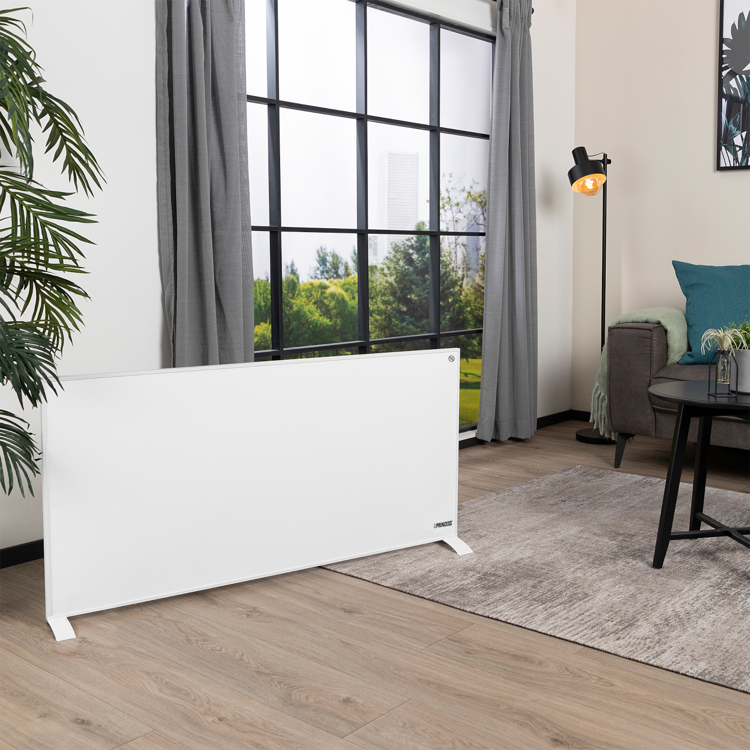 Ein weißer Elektroheizer in einem Raum, mit Fenster, Sofa und Lampe.