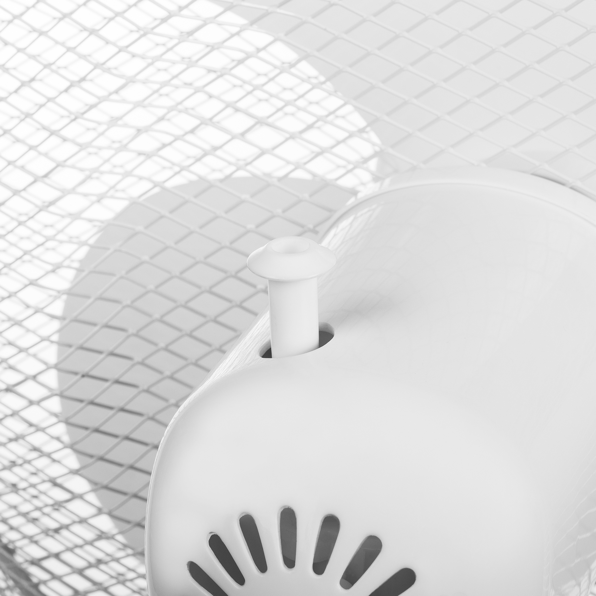 Nahaufnahme eines weißen Ventilators mit weißem Gitter. Ein zentraler weißer Steuerstab ist sichtbar.