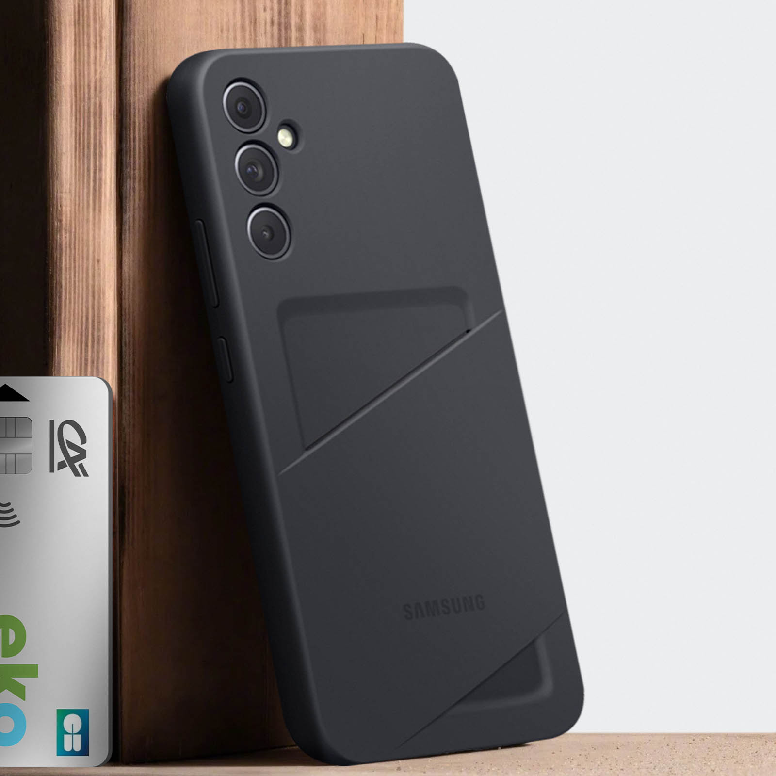 Czarny pokrowiec na telefon z kieszonką na portfel, oparty o drewno. Widoczna karta CA.