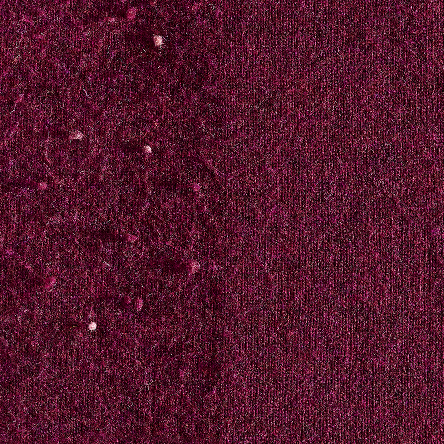 Nahaufnahme eines tiefroten Stoffes mit kleinen weißen Flecken, die über die Oberfläche verstreut sind.